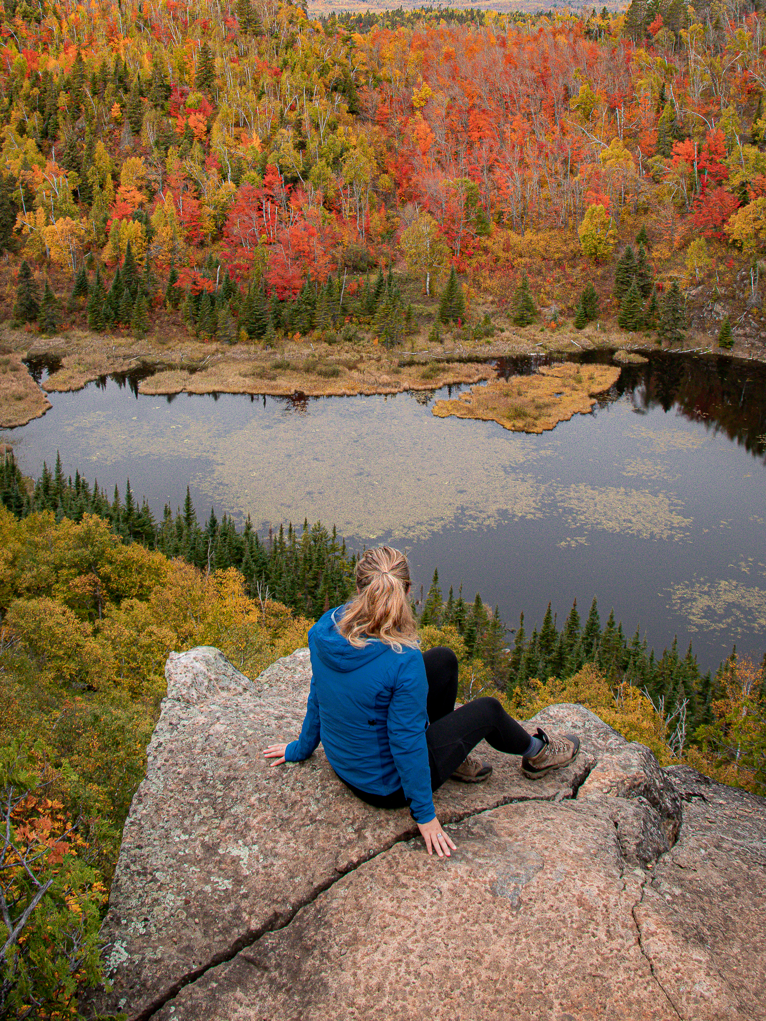 A hiker on a rock at a beaver pond at Fantasia Overlook off the Superior Hiking Trail, North Shore of Minnesota