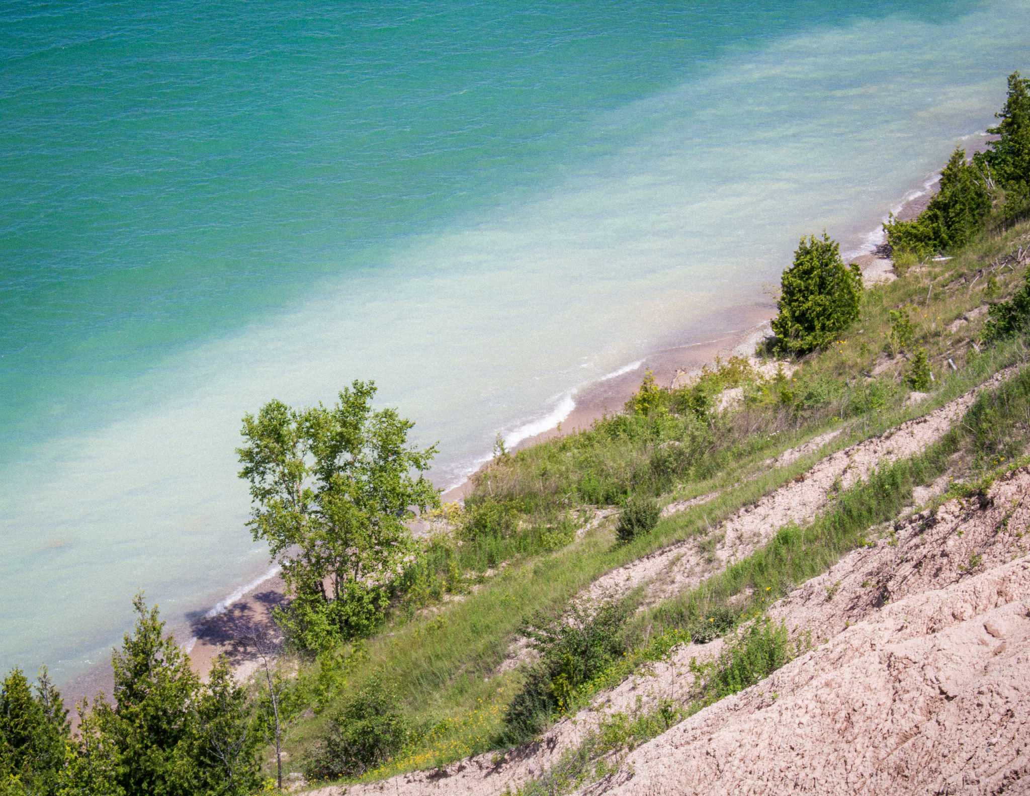 Clay Cliffs Natural Area near Traverse City Michigan hiking trail, looking down at blue Lake Michigan water from the hiking trail