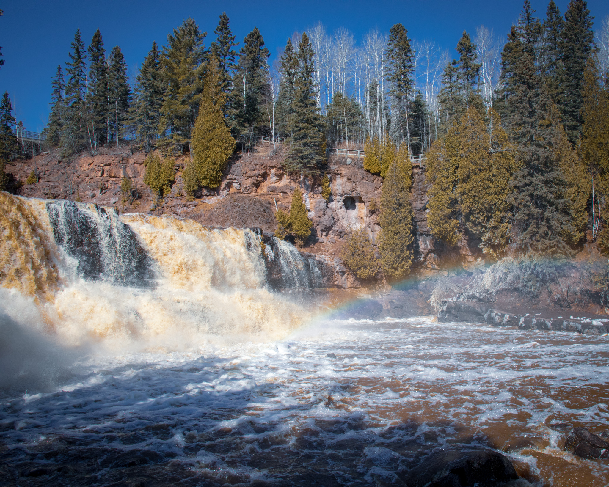 Image of part of Gooseberry Falls Waterfall with a rainbow in the waterfall mist