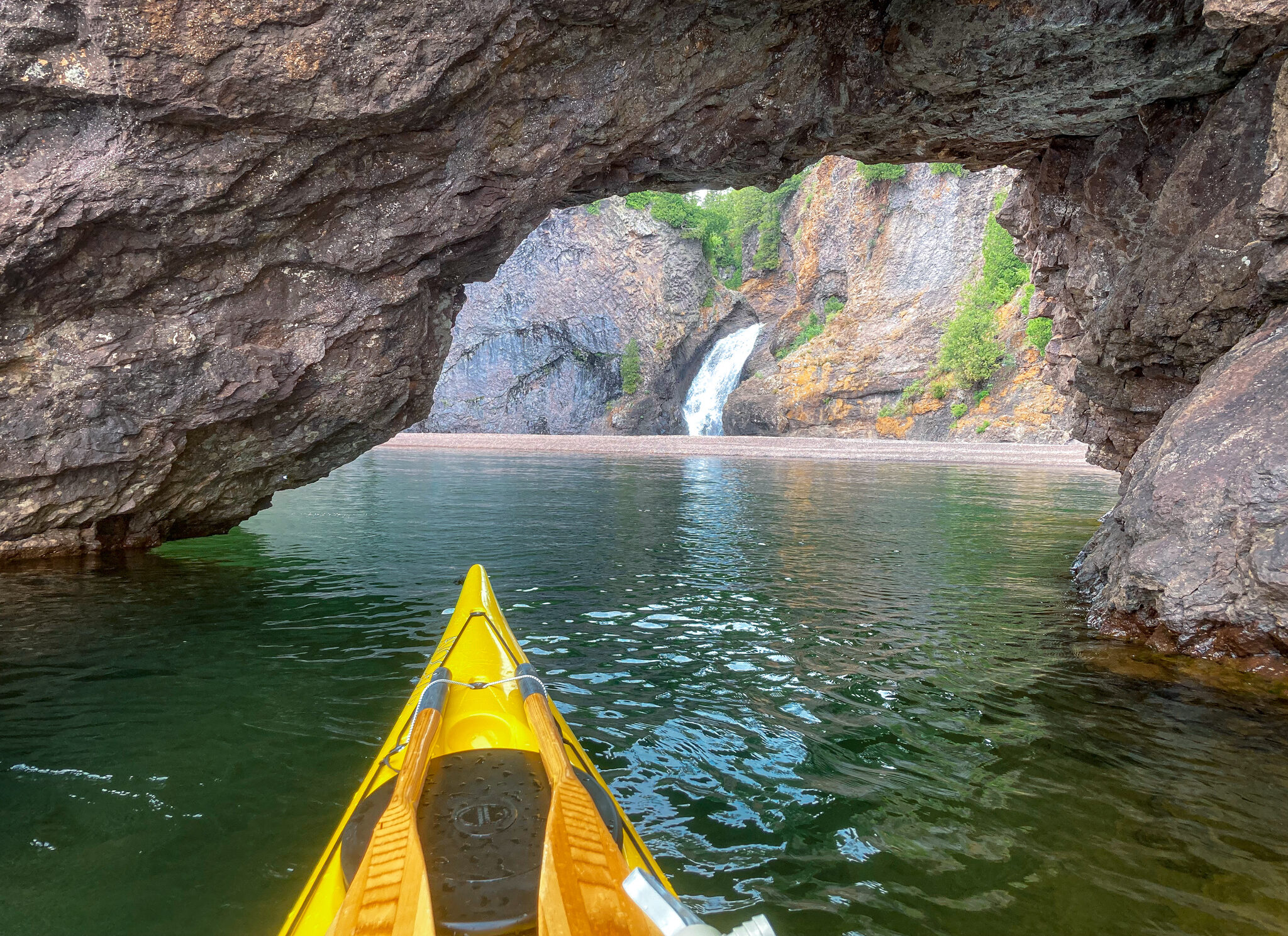 image of Manitou Falls on Lake Superior through a sea arch on the North Shore of Minnesota