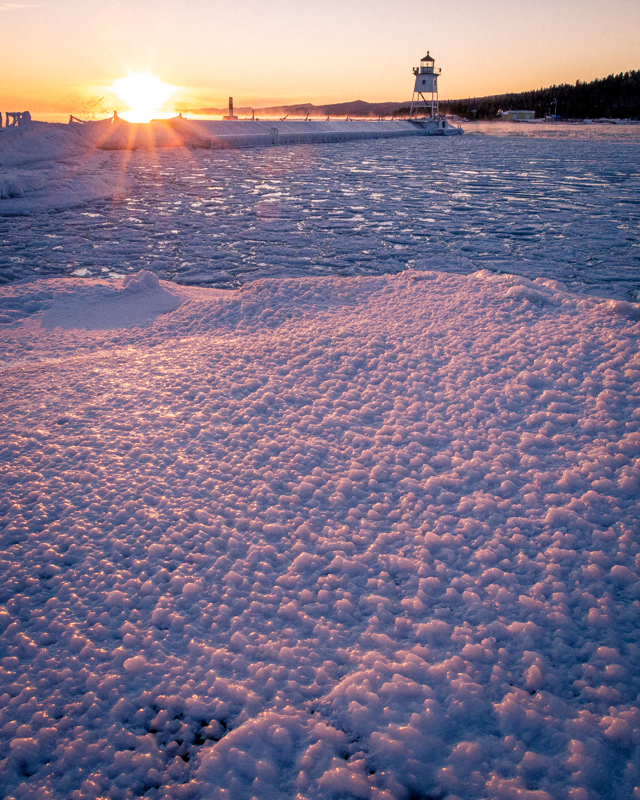Sunset over ice at the Grand Marais lighthouse in Northern Minnesota on lake superior