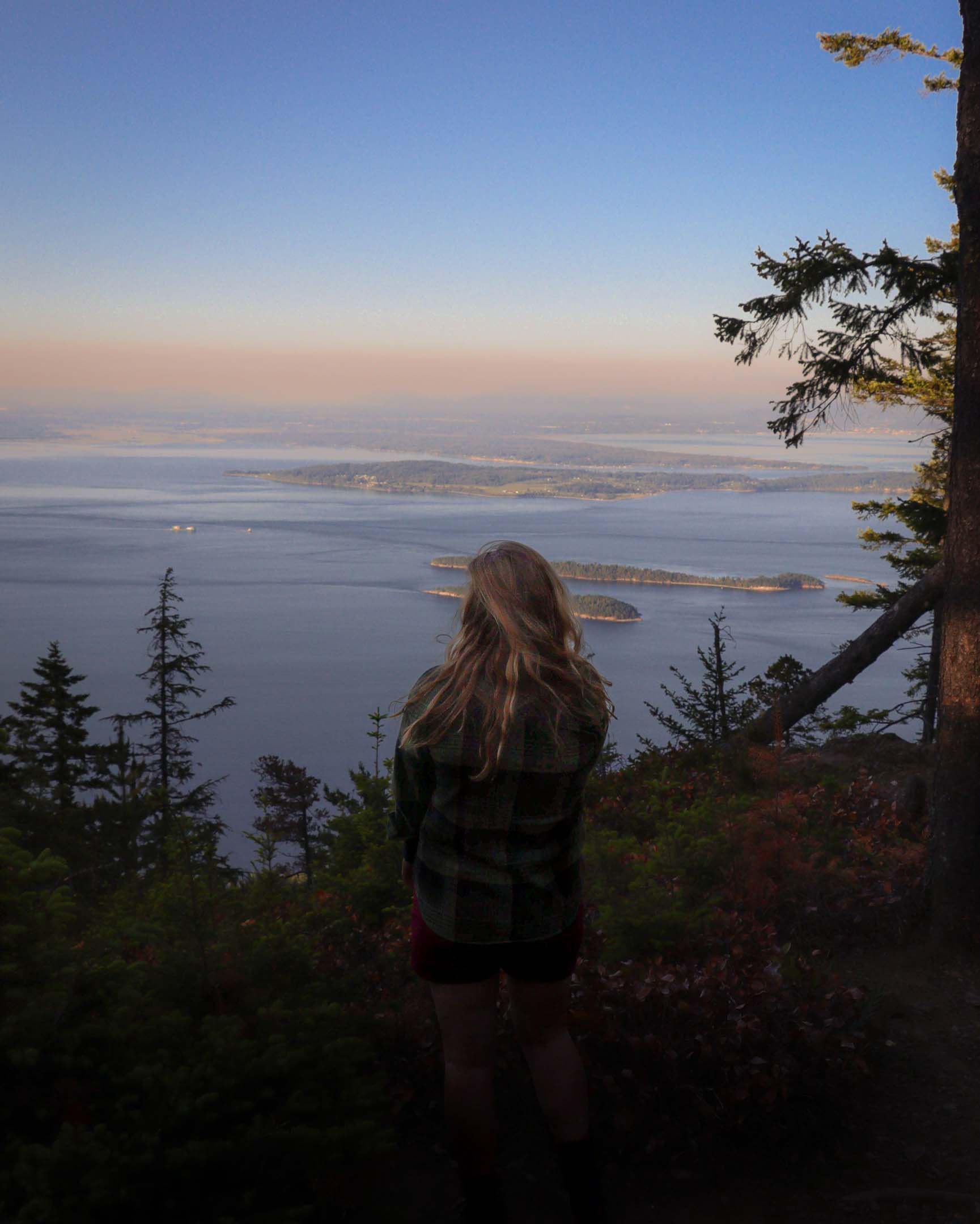 A hiker on Orcas Island at an overlook looks out over the San Juan Islands below