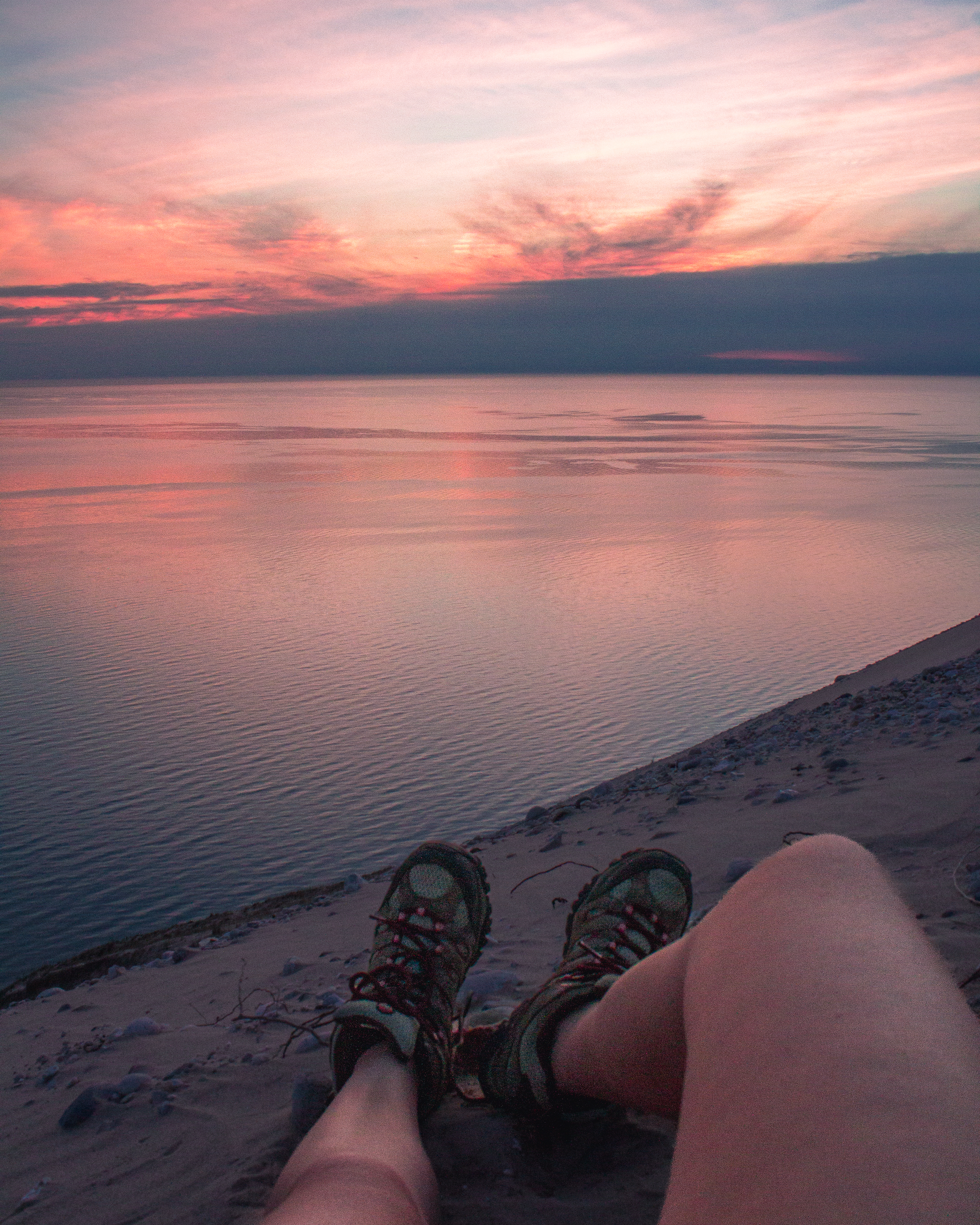 a hikers legs in front of a sunset overlooking Lake Michigan in the Sleeping Bear Dunes