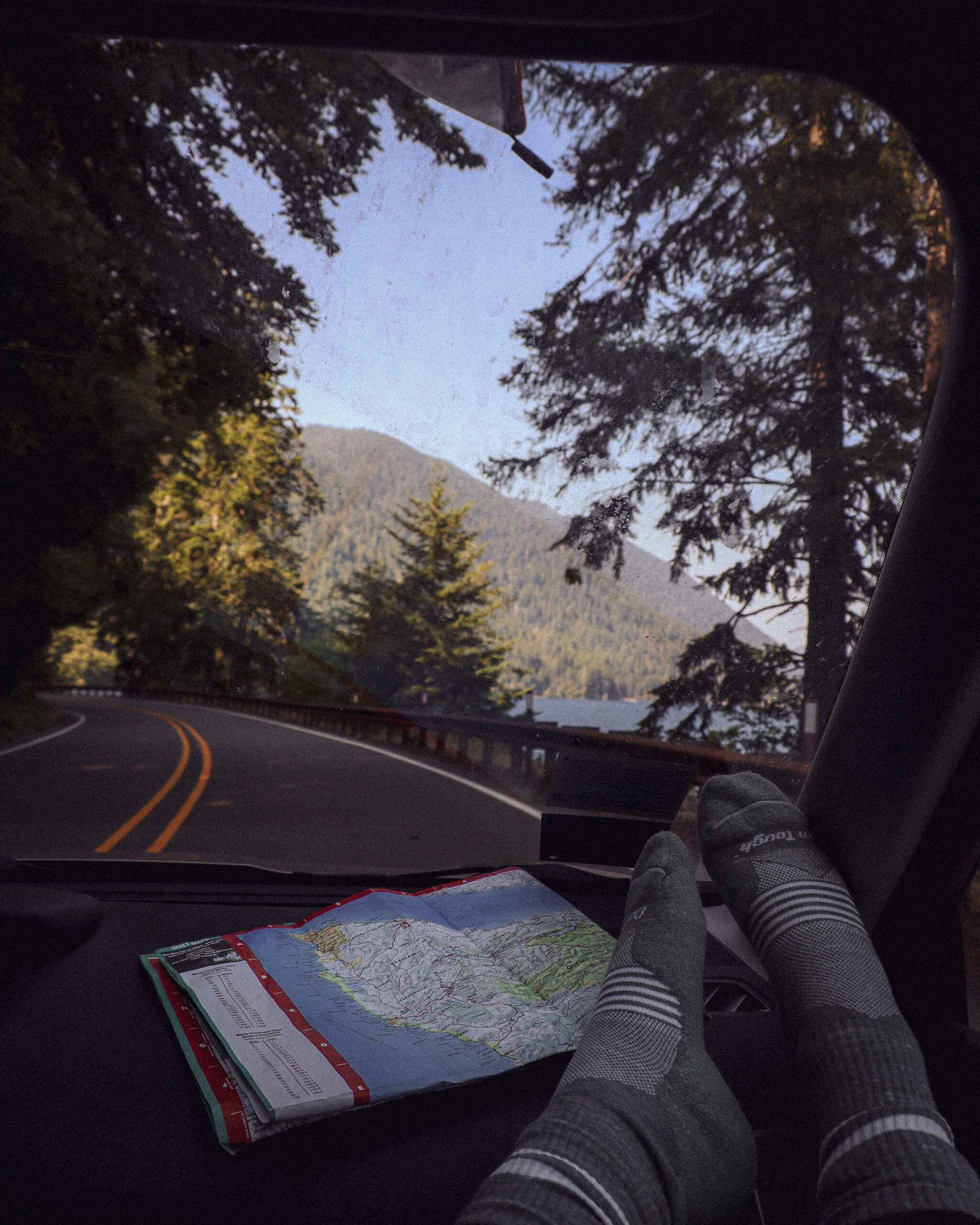 A map of the olympic peninsula sits on a car dashboard while driving through Olympic National Park