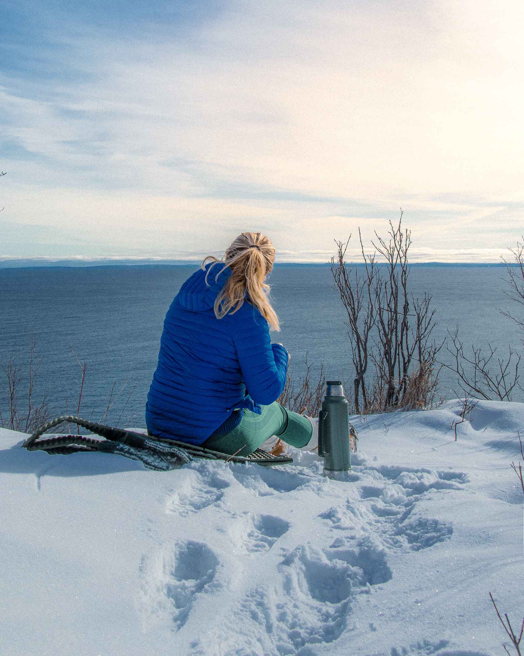 A hiker sits on an overlook of Lake Superior wearing baselayer pants