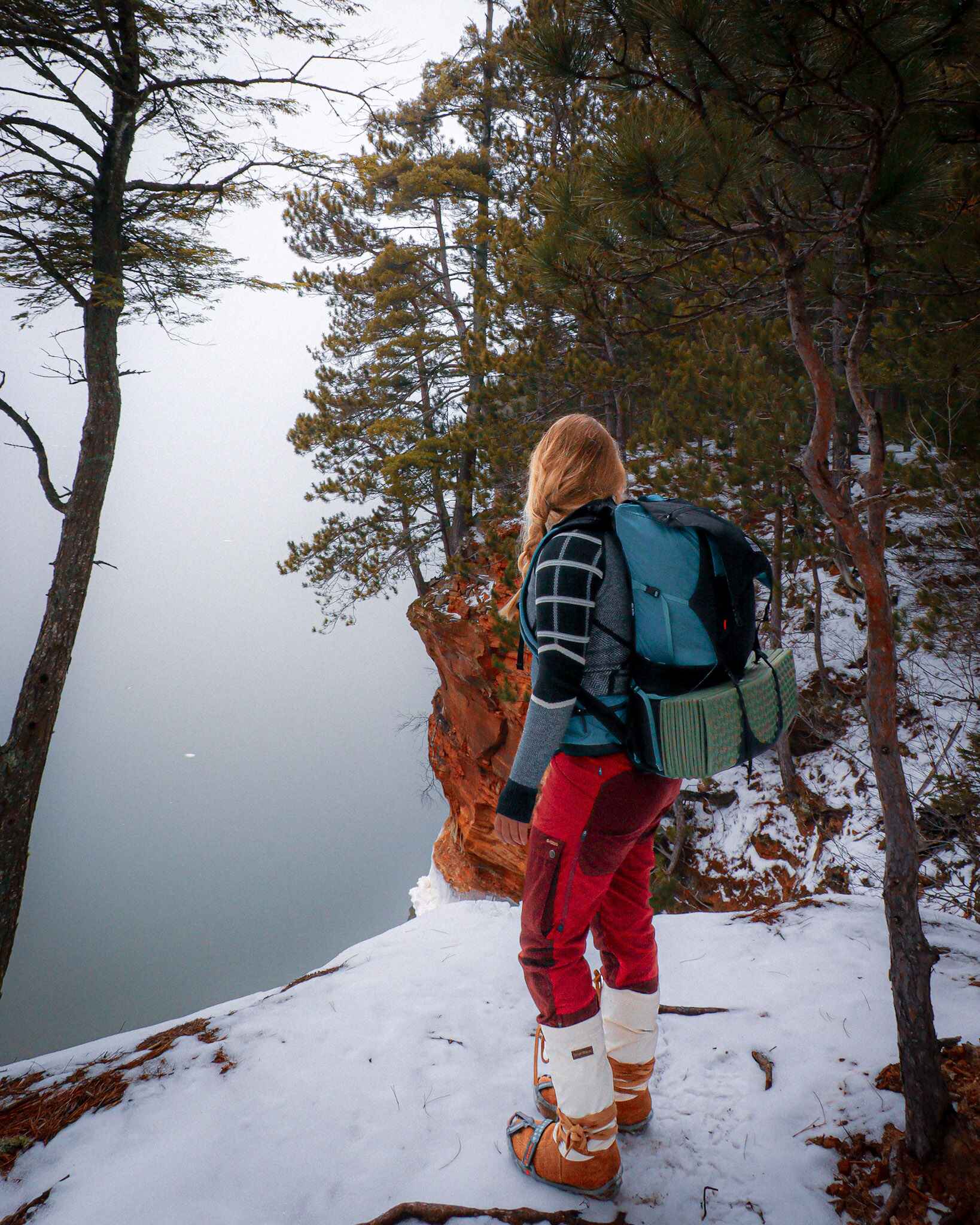 image of hiker hiking above the apostle islands ice caves in bayfield, WI in the winter