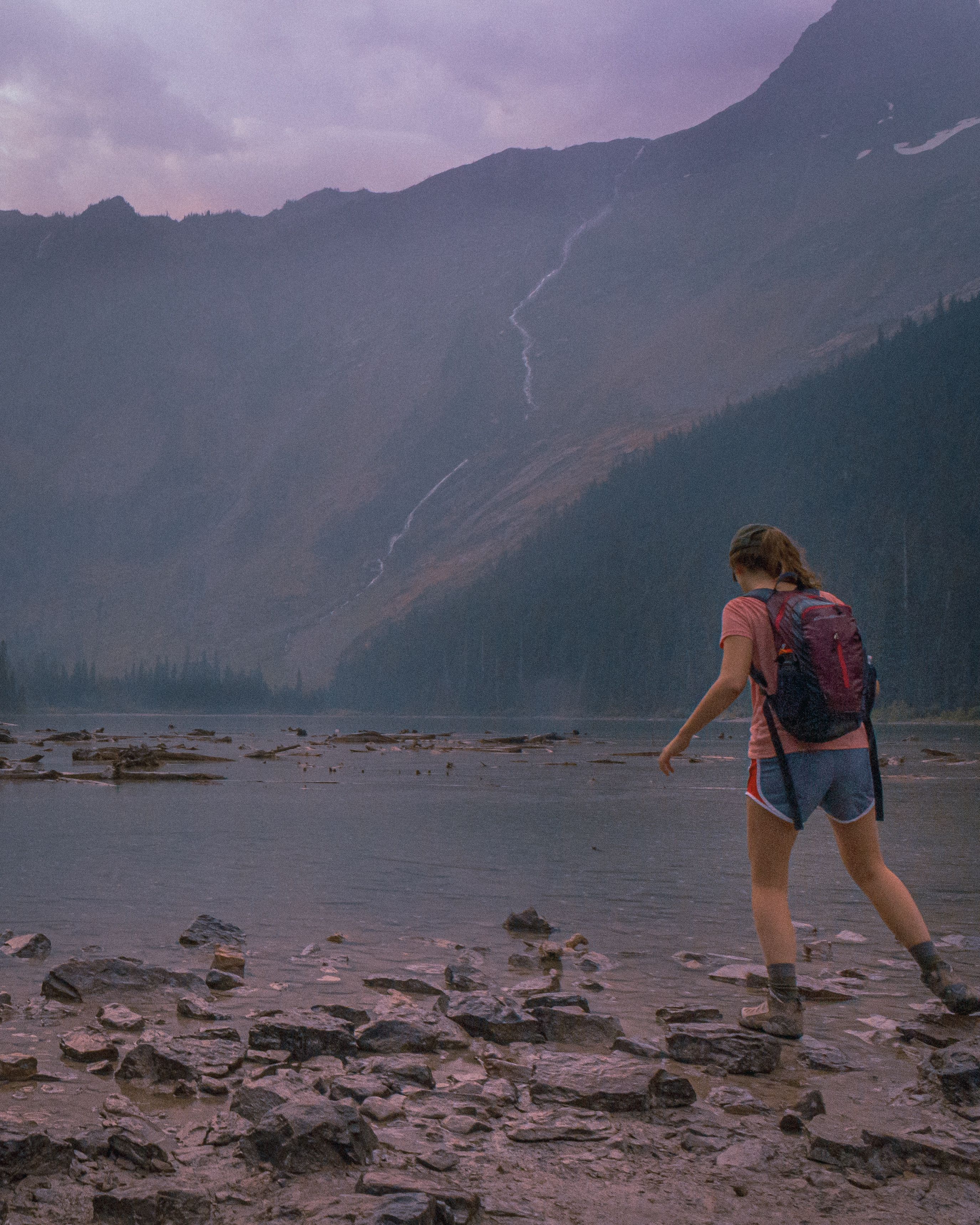 a hiker skips on rocks at Avalanche Lake in Glacier National Park