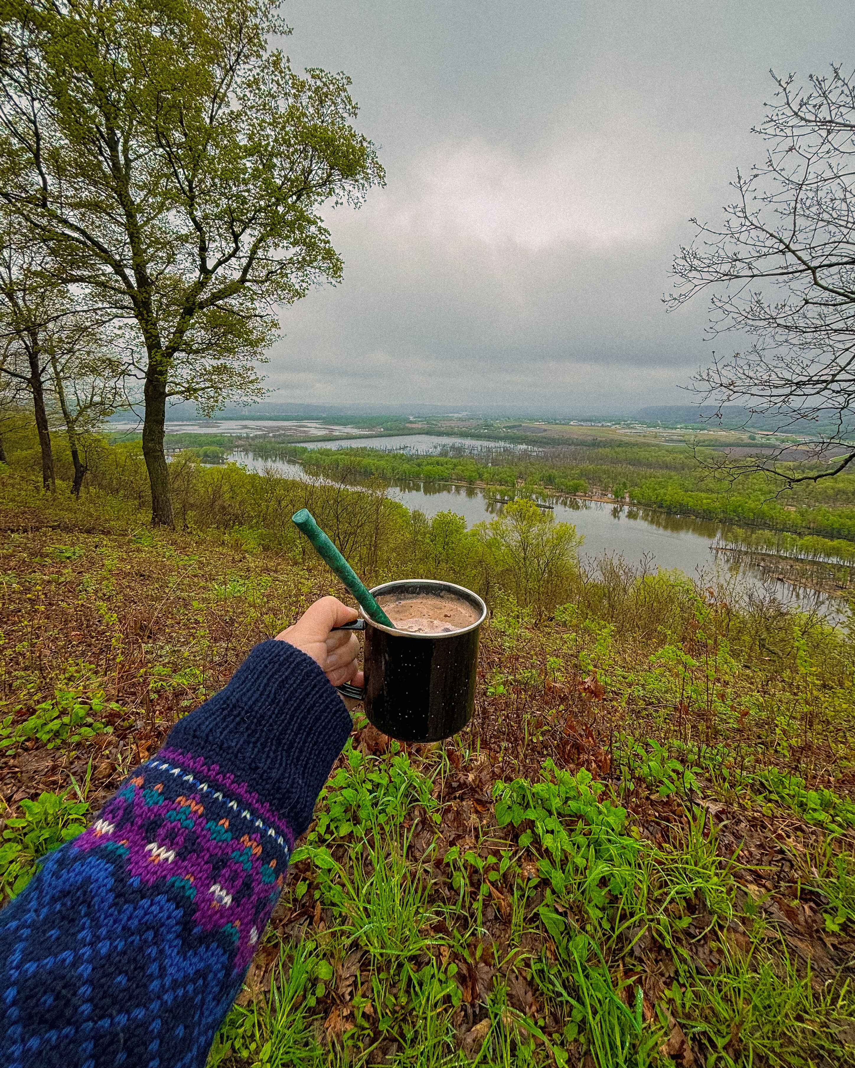 a hiker in a wool sweater with a hot coco pauses to take in the view at Wyalusing State Park, Wisconsin