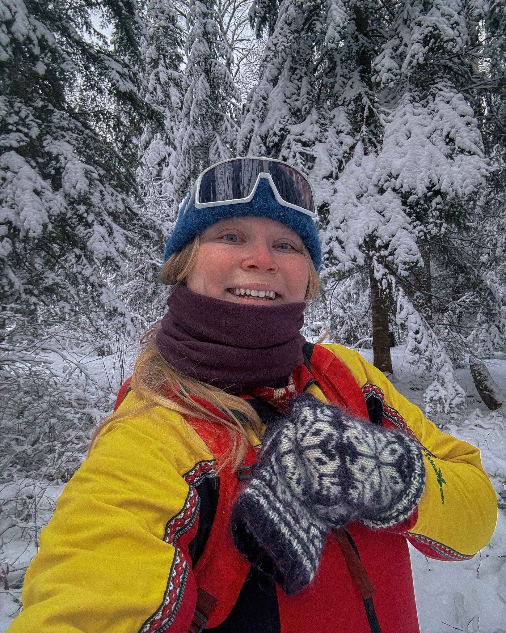 a hiker smiles into the camera in the winter woods