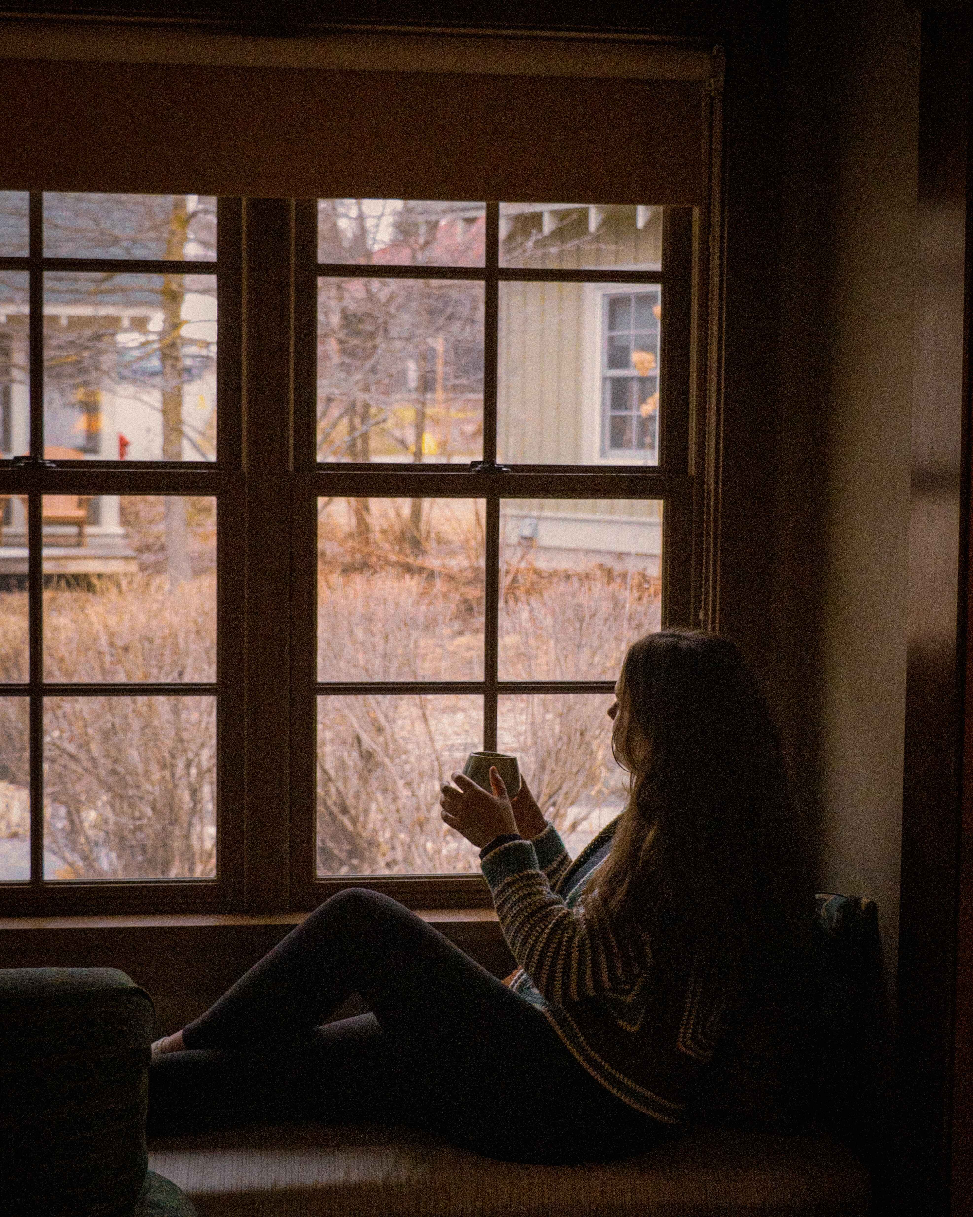 a woman sits in a window at a cabin at crystal mountain resort