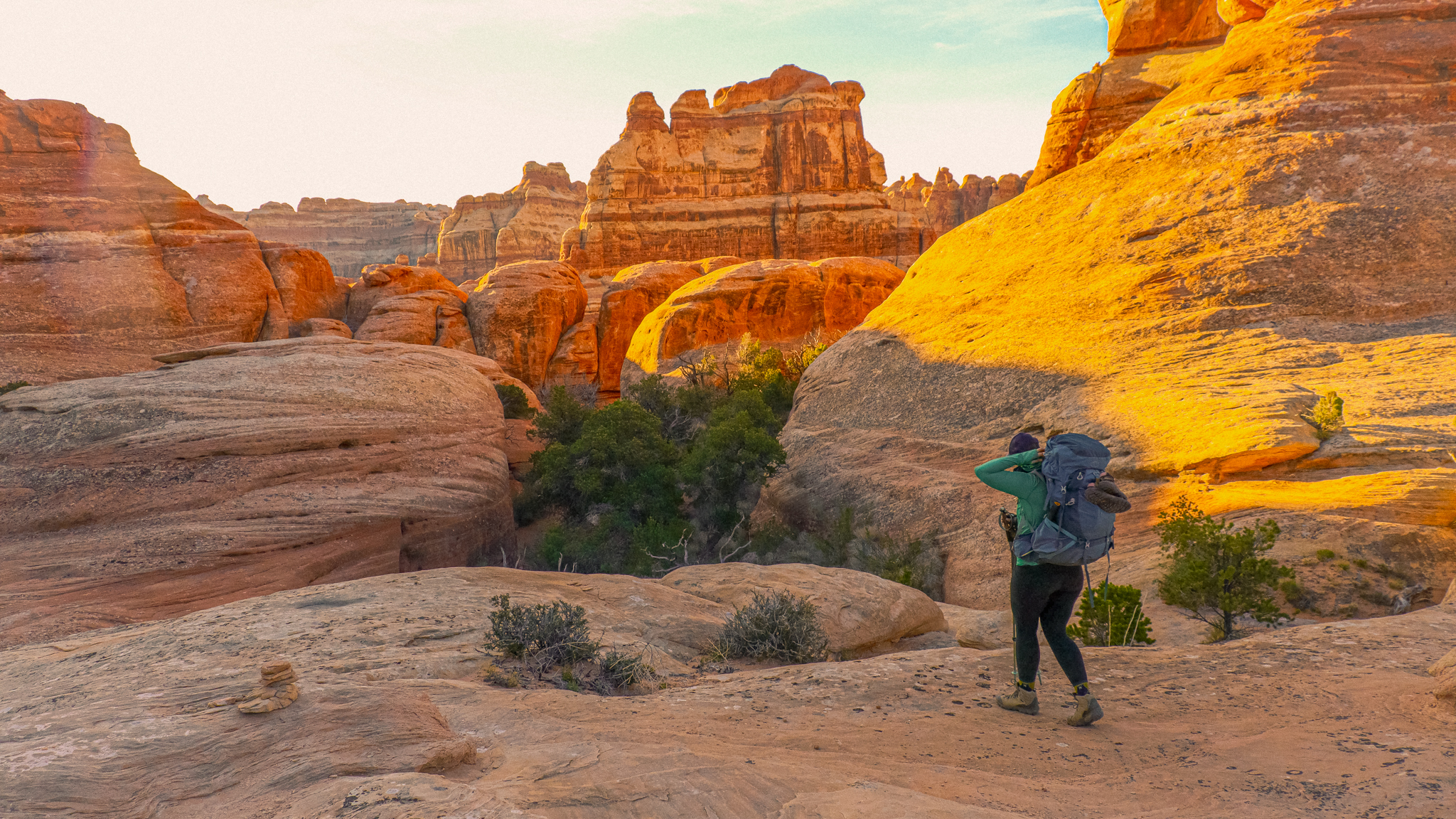 image of a woman hiking with a large backpacking bag on through red rock of canyonlands naitonal park in utah