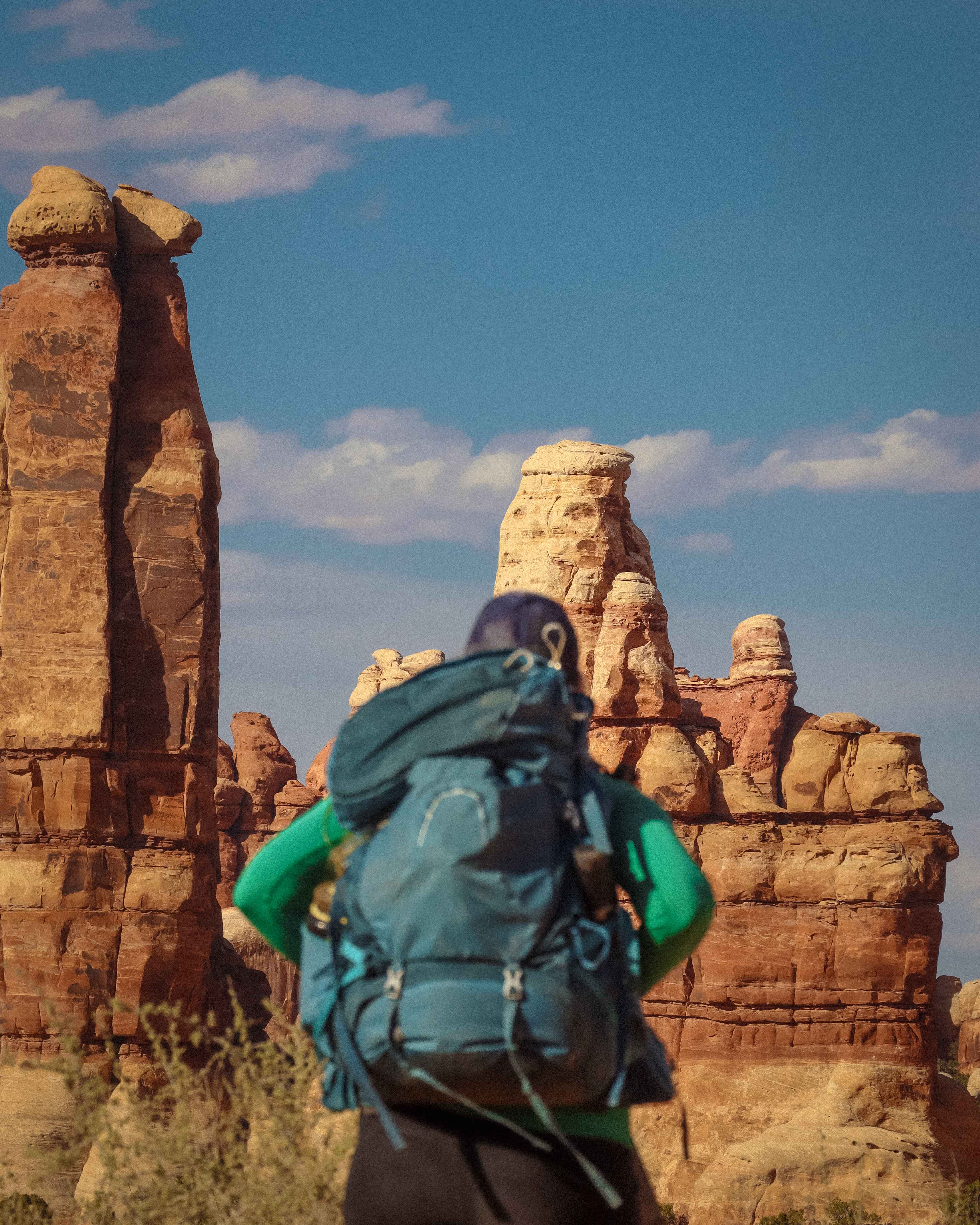 a backpacker stands in front of hoodos in the needles district of canyonlands national park