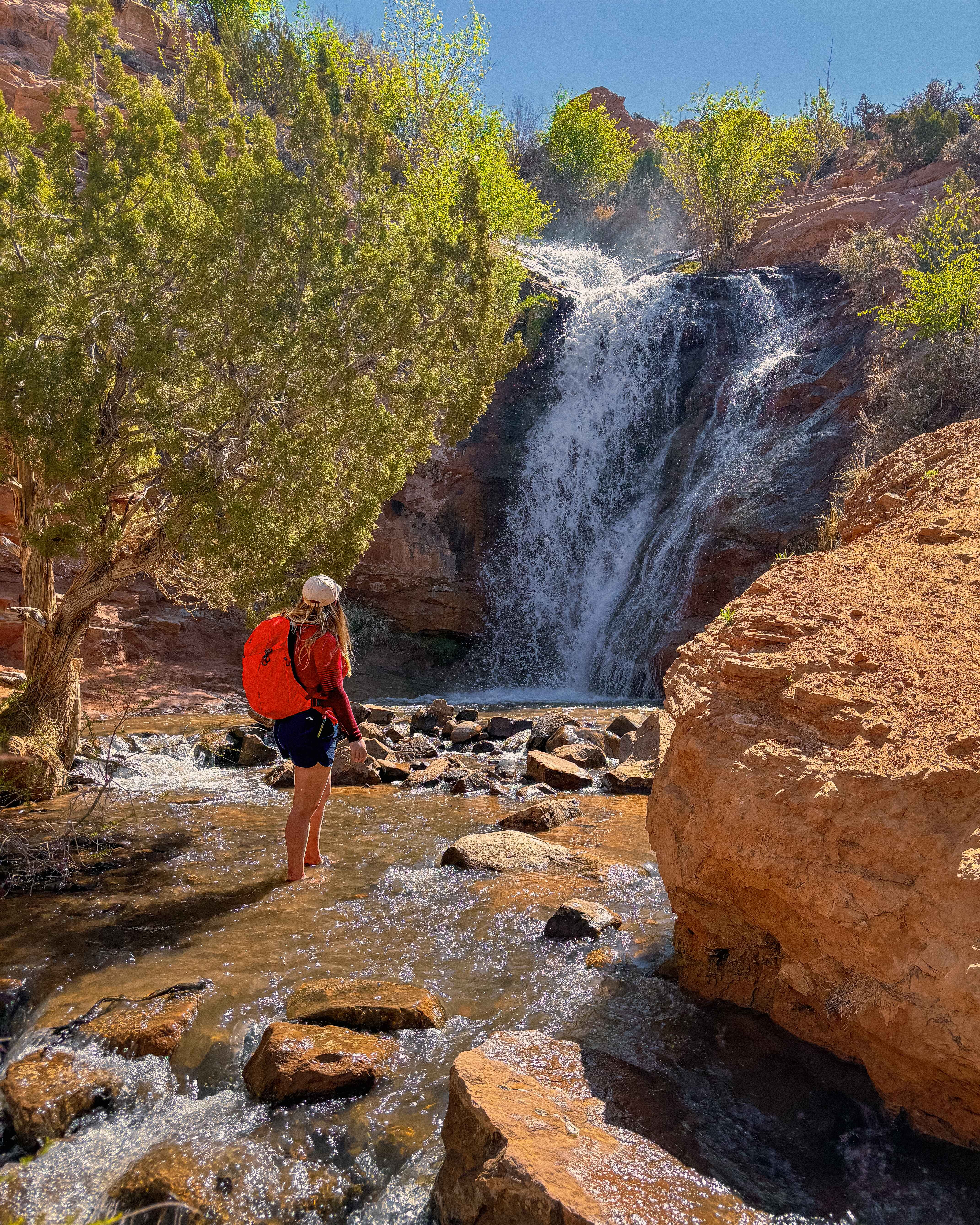 Hiker in front of a waterfall near Ken's Lake just outside of Moab, Utah
