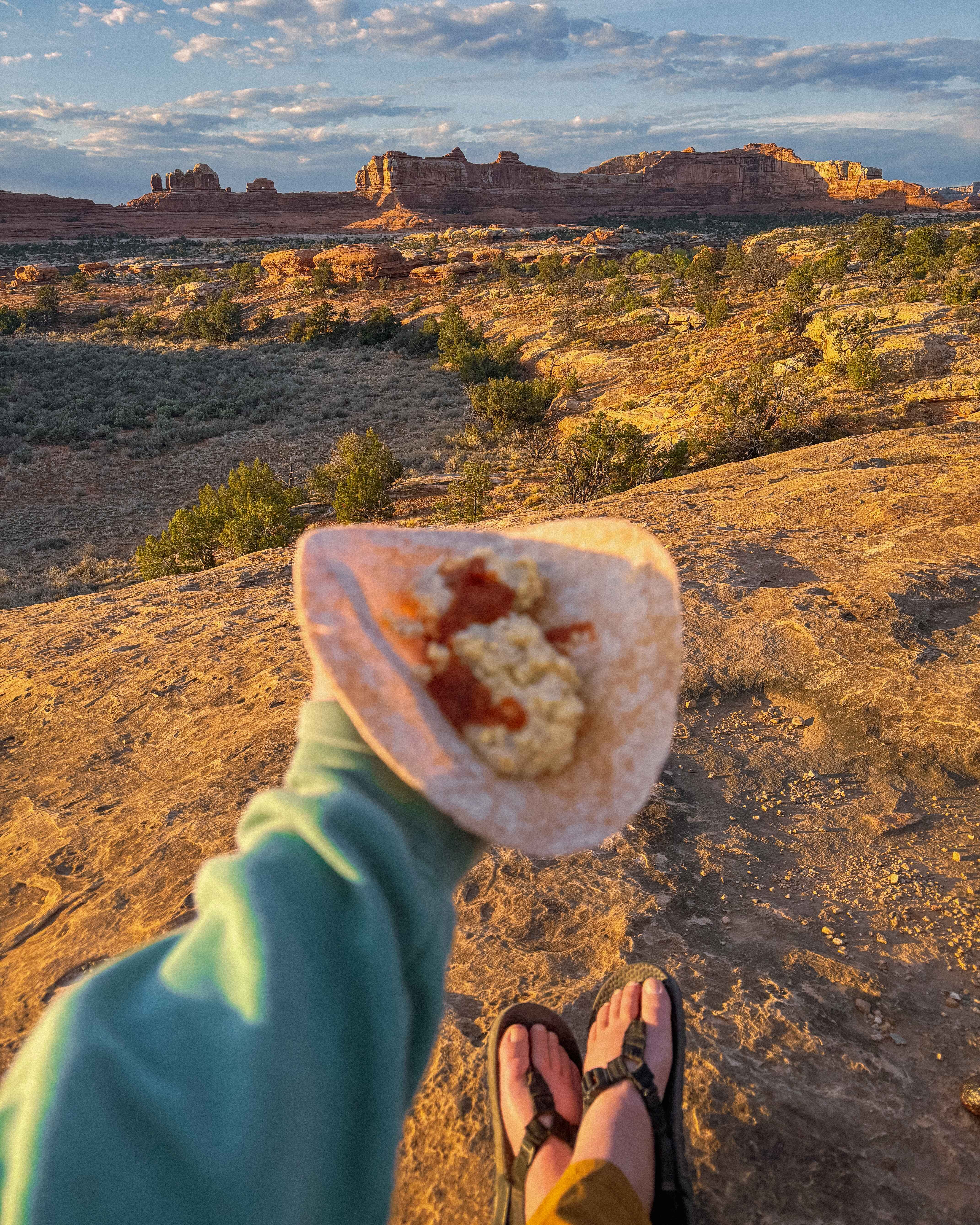 a camp meal in held up by a hiker in front of a view of the desert outside of canyonlands national park, Utah