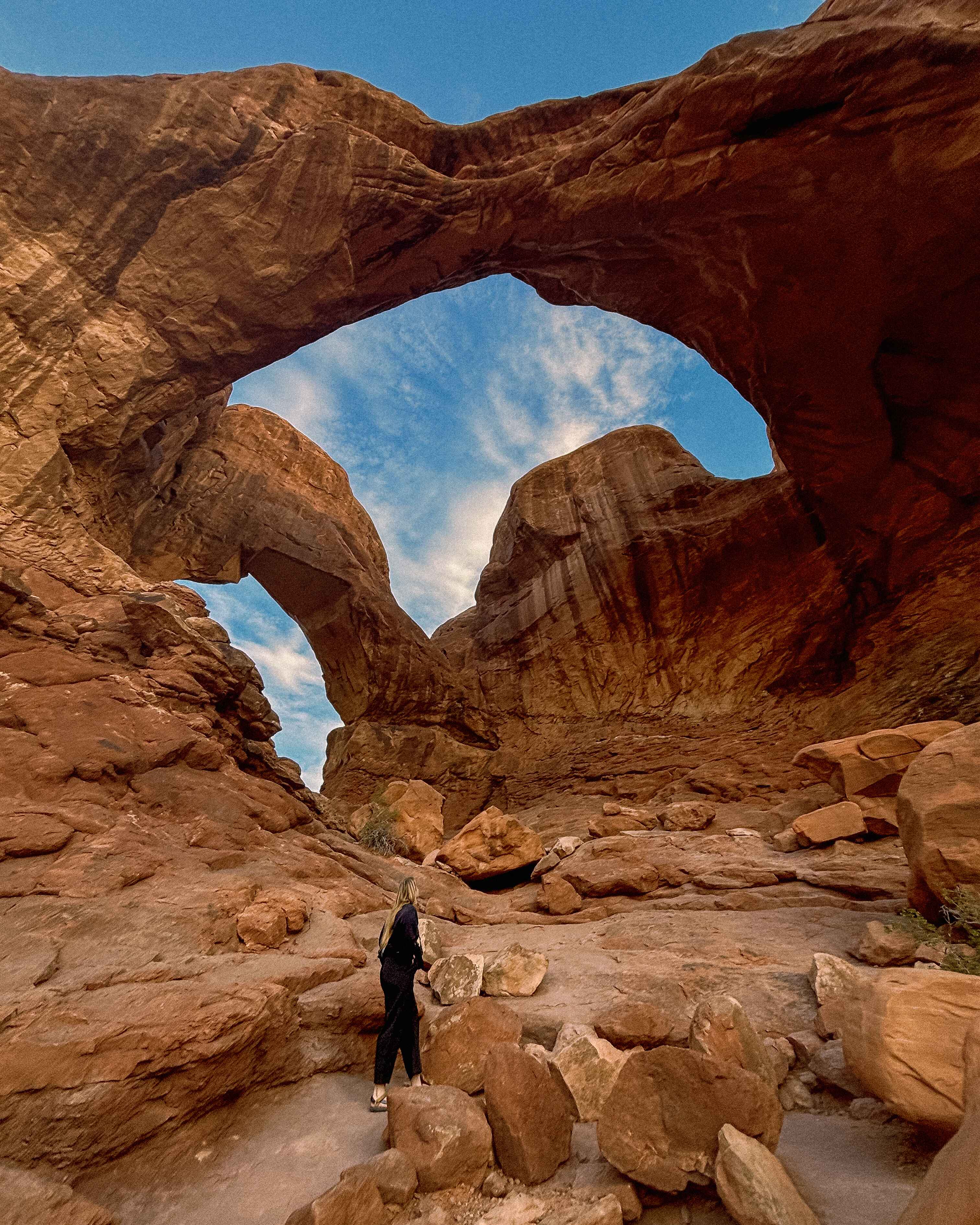 A hiker in front of Double Arch in Arches National Park near Moab