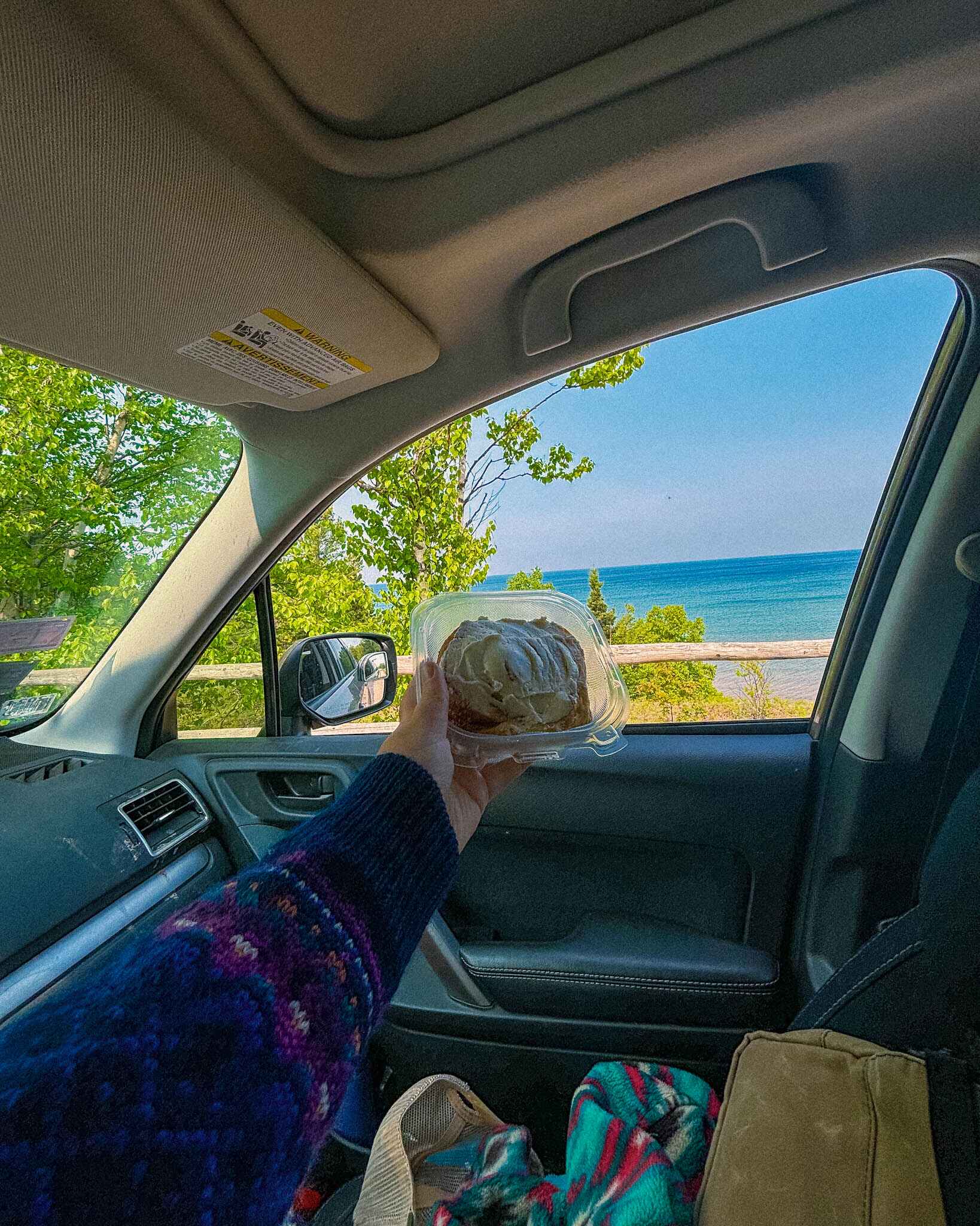 Image of a cinnamon roll in front of Great Sand Bay lookout in the Keweenaw Peninsula