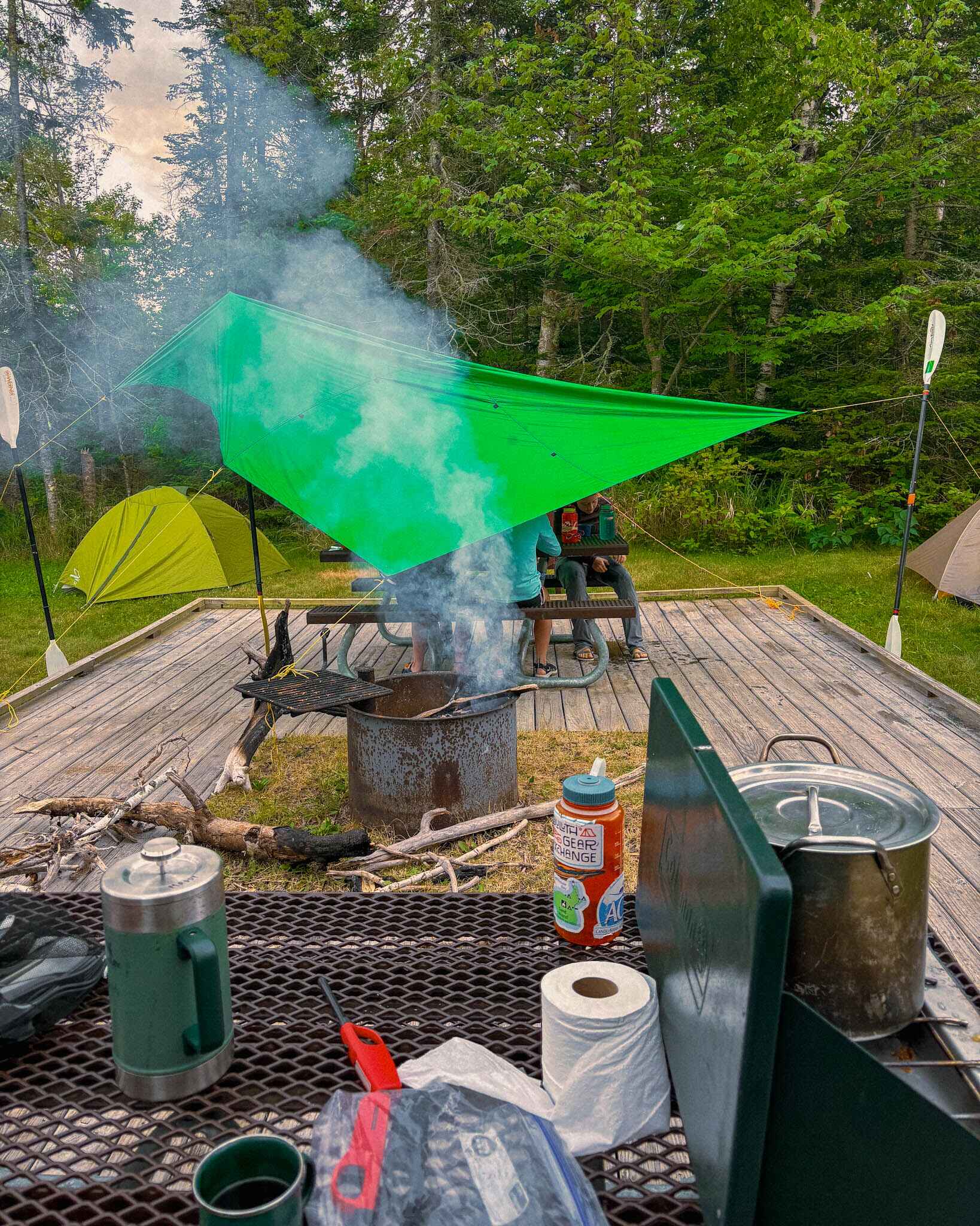 Image of a kids group camp setup with a Coleman double burner camping stove with a very impressive paddle tarp set up over the kids 