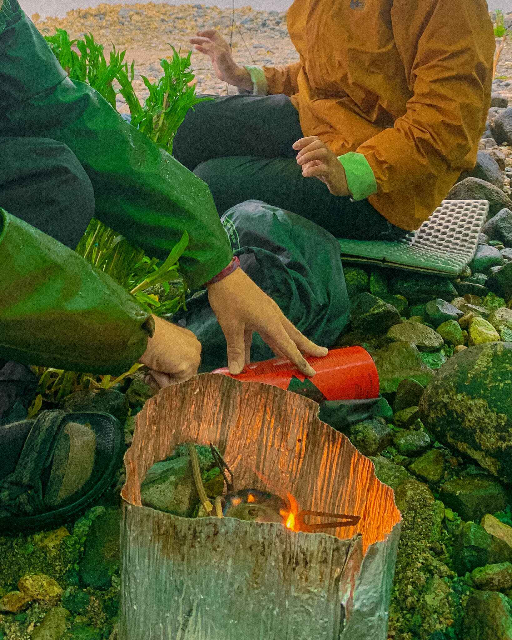 Image that shows the setup of the MSR Whisperlite camp stove. Fuel as white gas is on the outside, connected via a tube to the stove. A man pumps the fuel as the stove flames. A thin metal wall protects the stove's flame. 