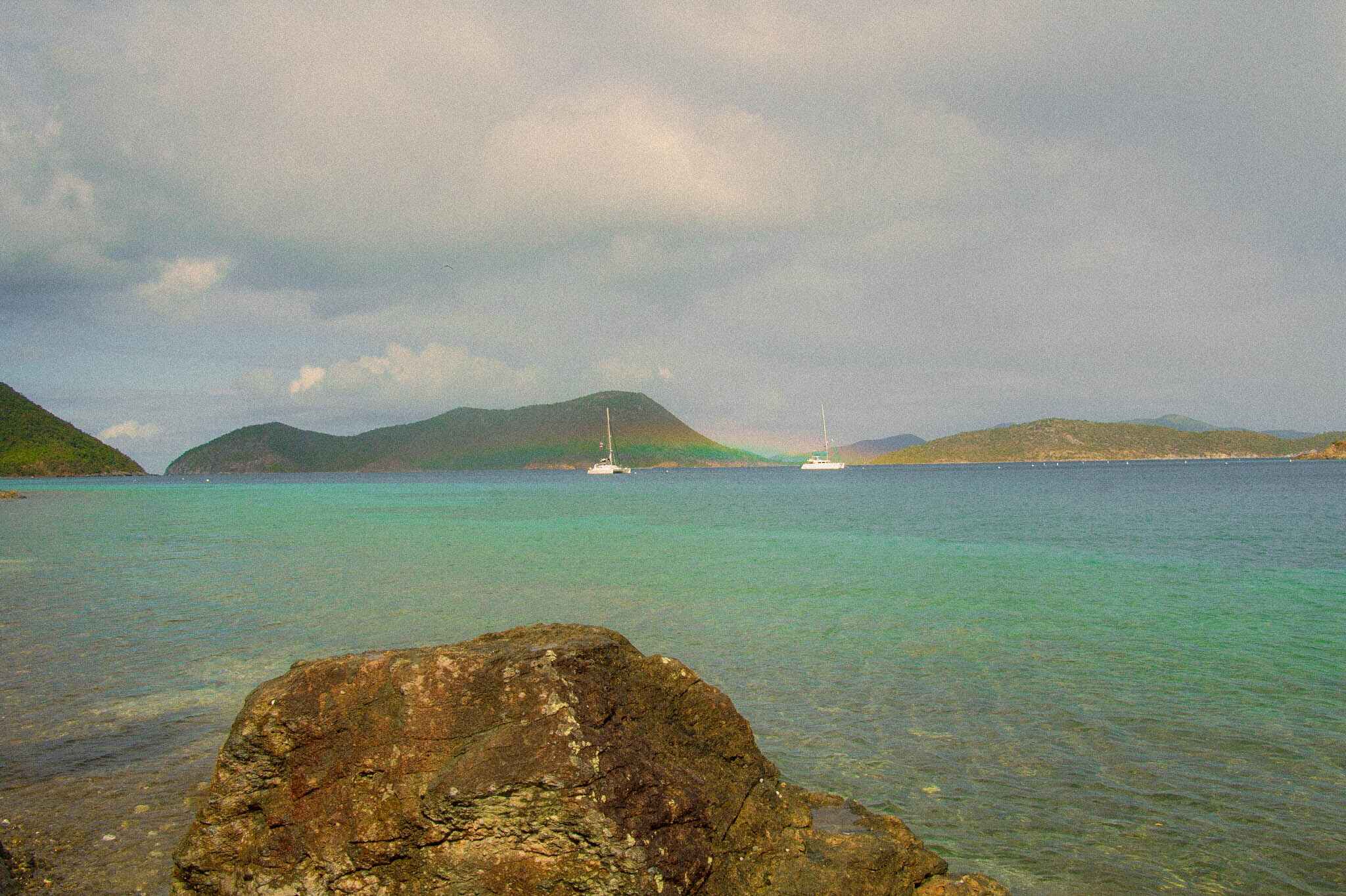 Sailboats with a rainbow behind them, with clear blue water in front, Virgin Islands National Park