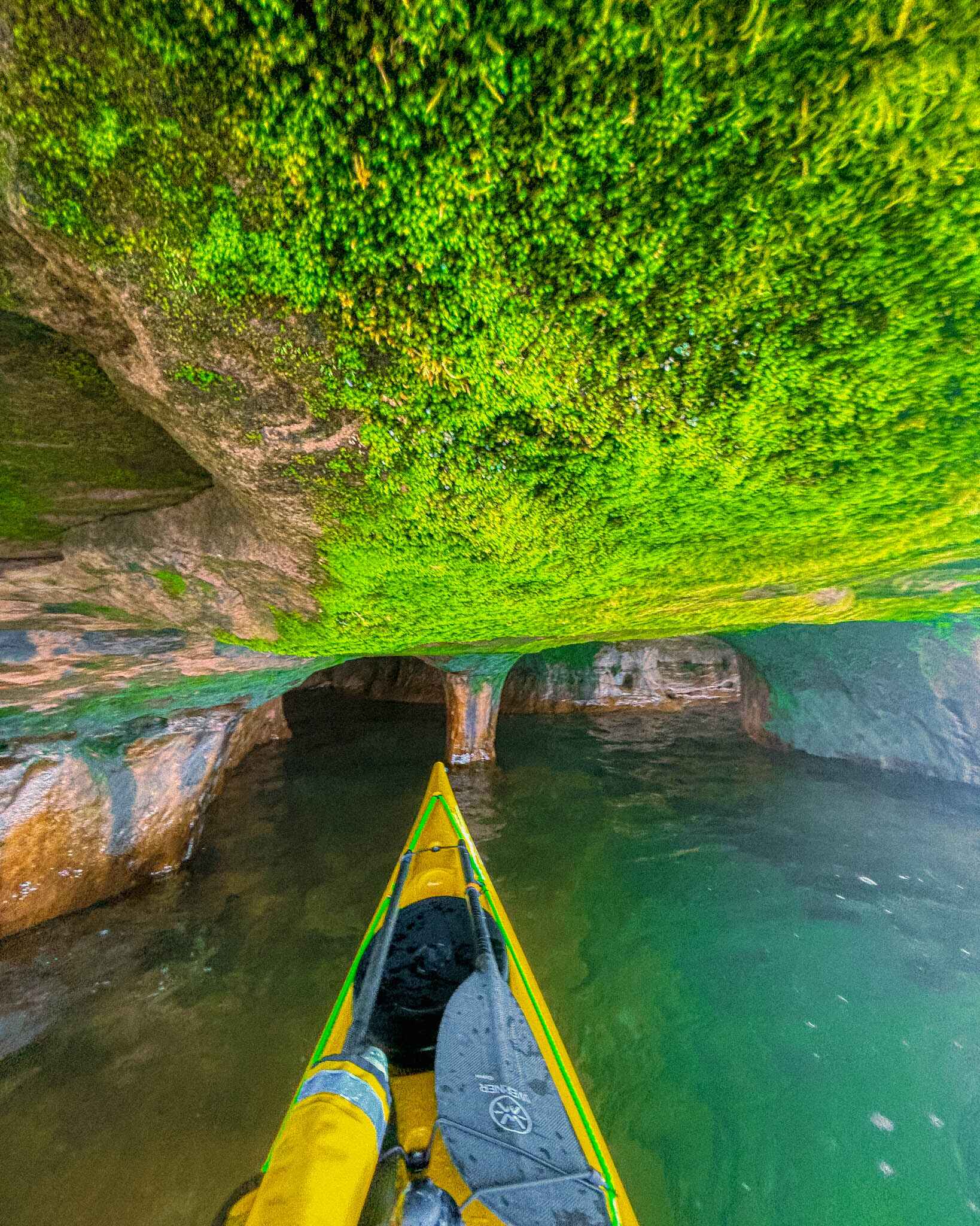 a kayak in a green and mossy sea cave in the apostle islands, wisconsin