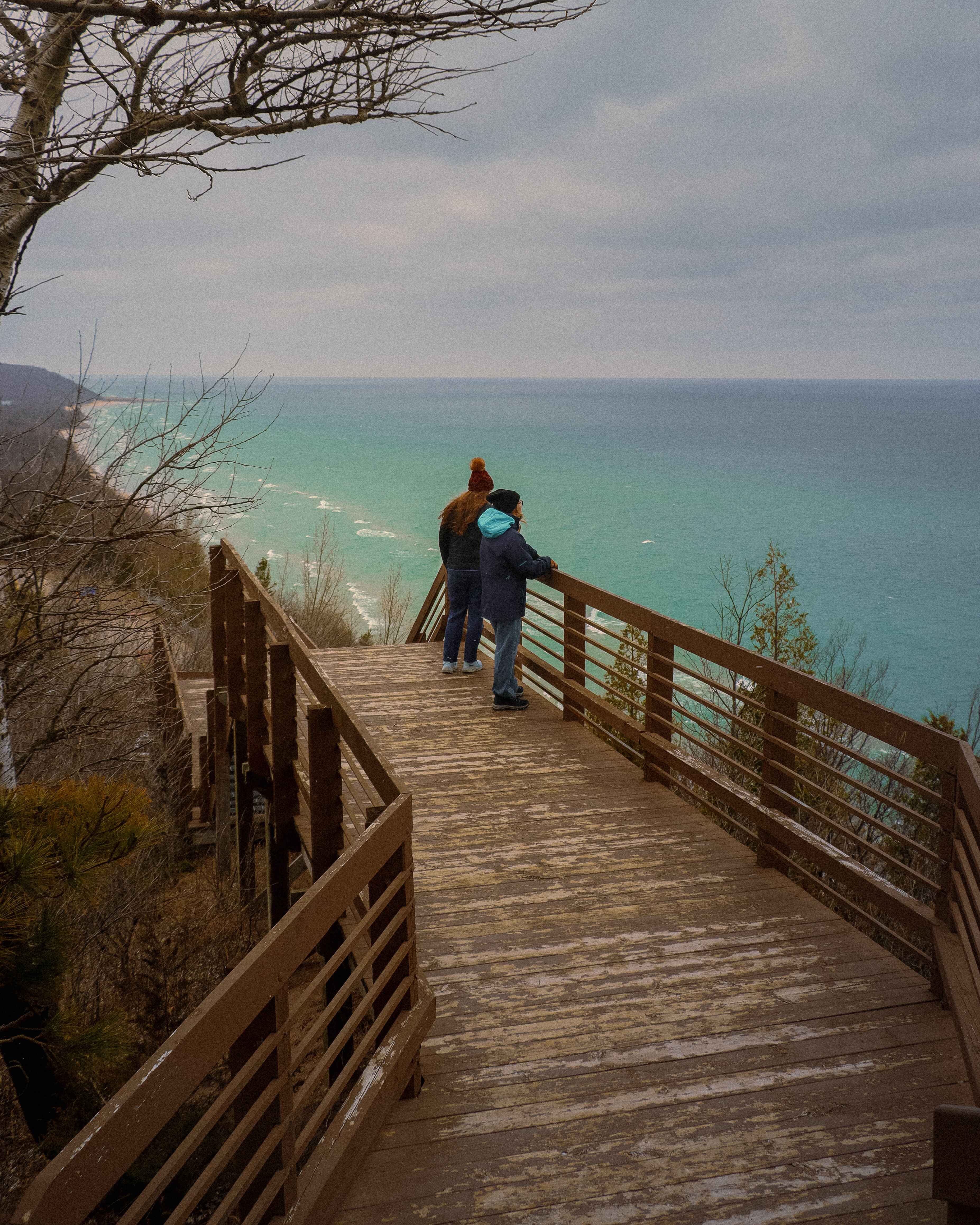 two hikers look out over Lake Michigan in the winter near Frankfort, Michigan