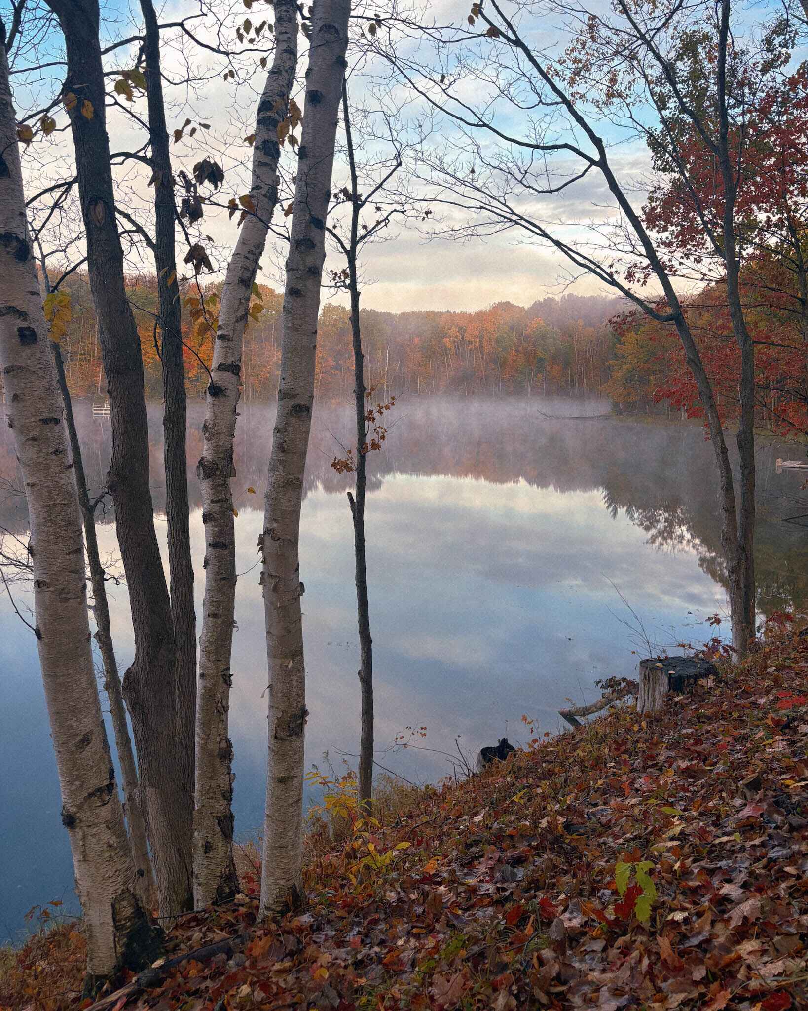 a steamy lake in the morning with fall colors all around near Traverse City, Michigan