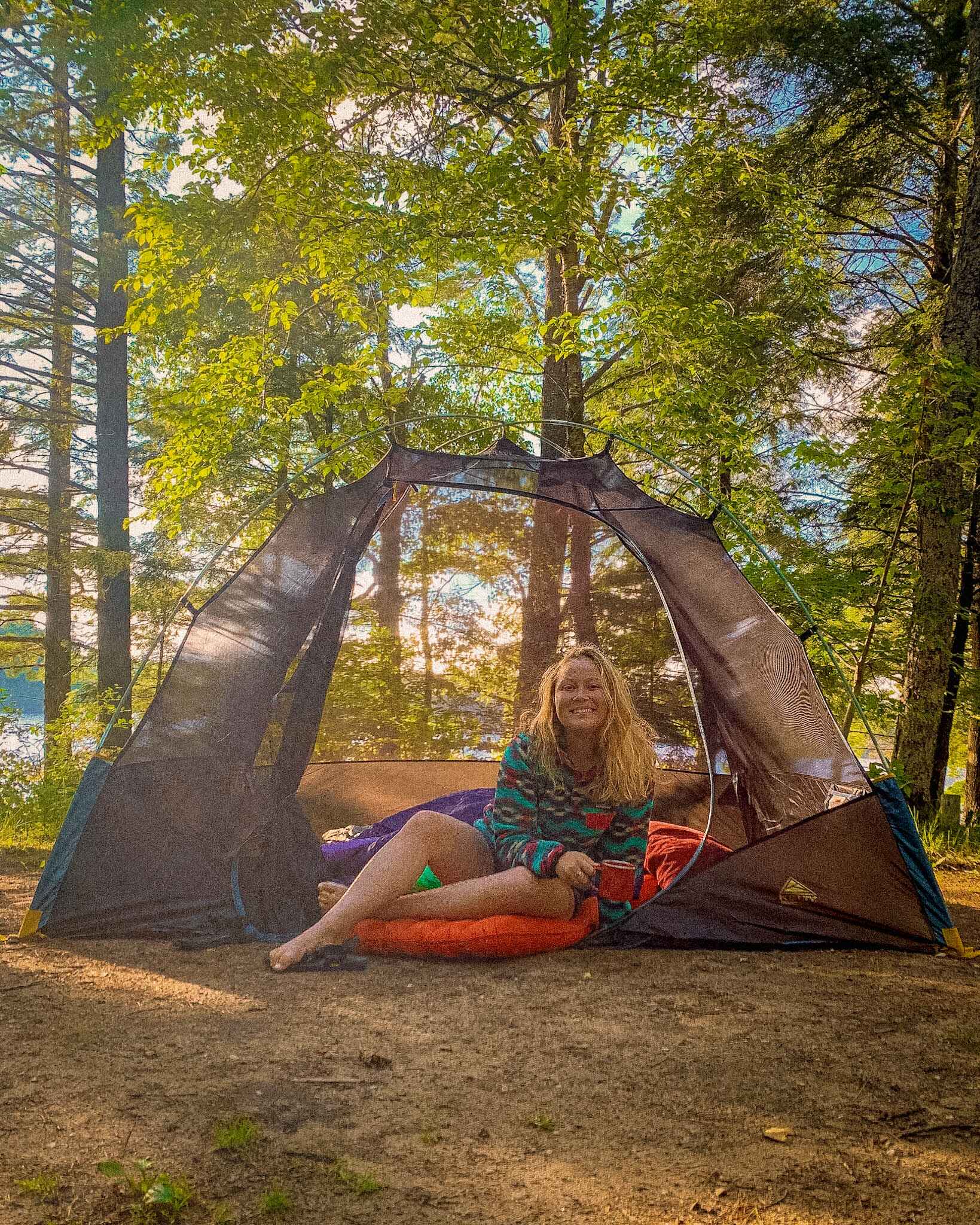 image of a blonde woman in a Kelty Discovery camping tent in the woods without a rainfly on