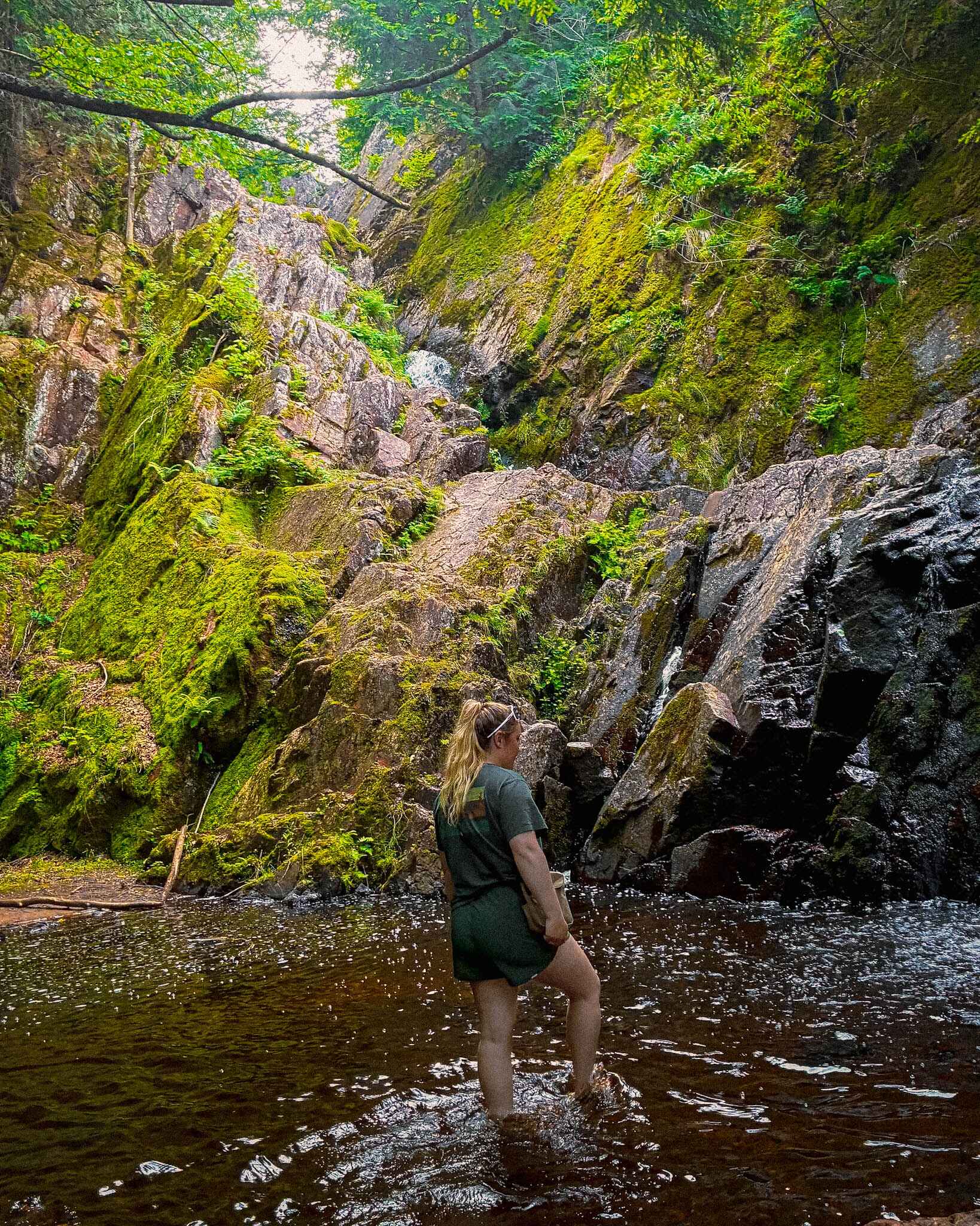 a hiker wades in a water fall wearing running shorts as hiking shorts