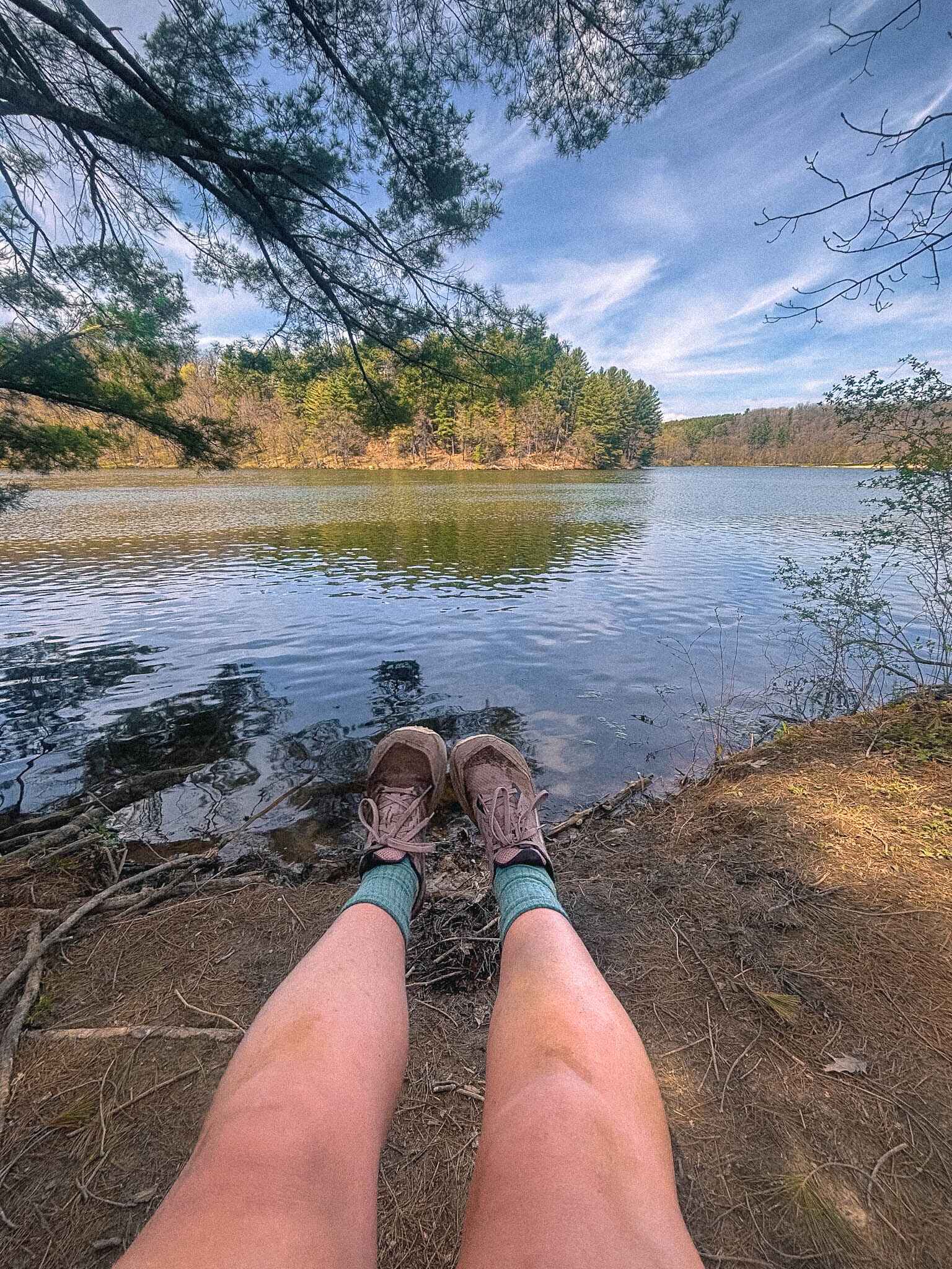 Image of a hiker's dirty legs in front of a lake