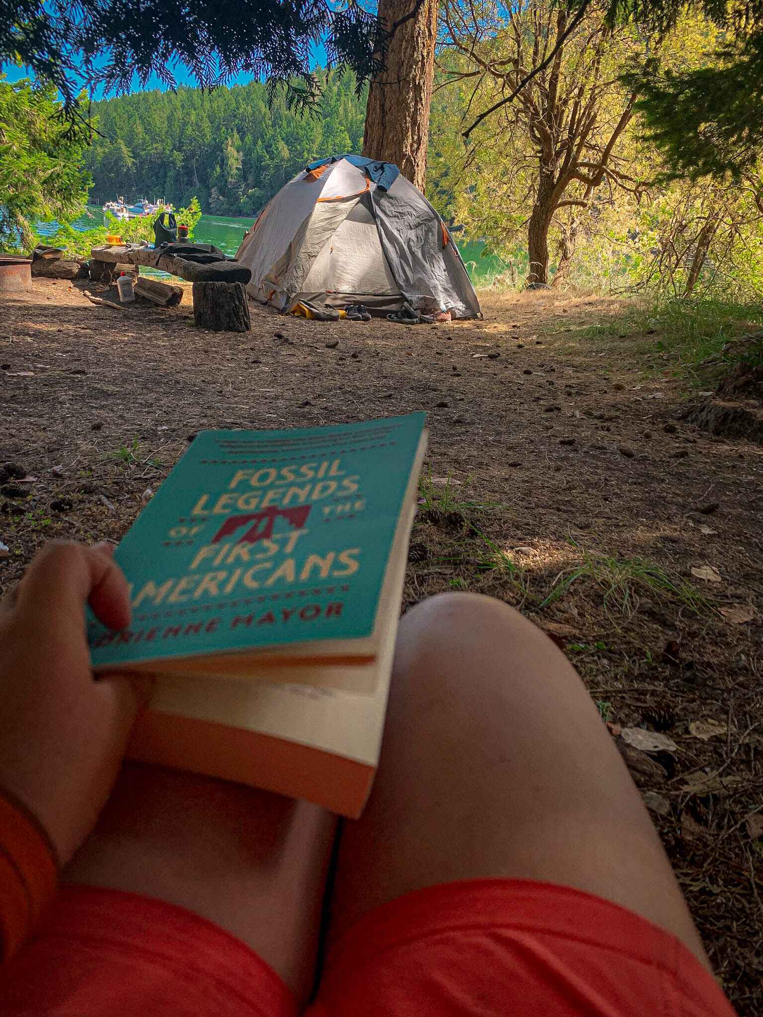 A hiker sits at camp in belted shorts