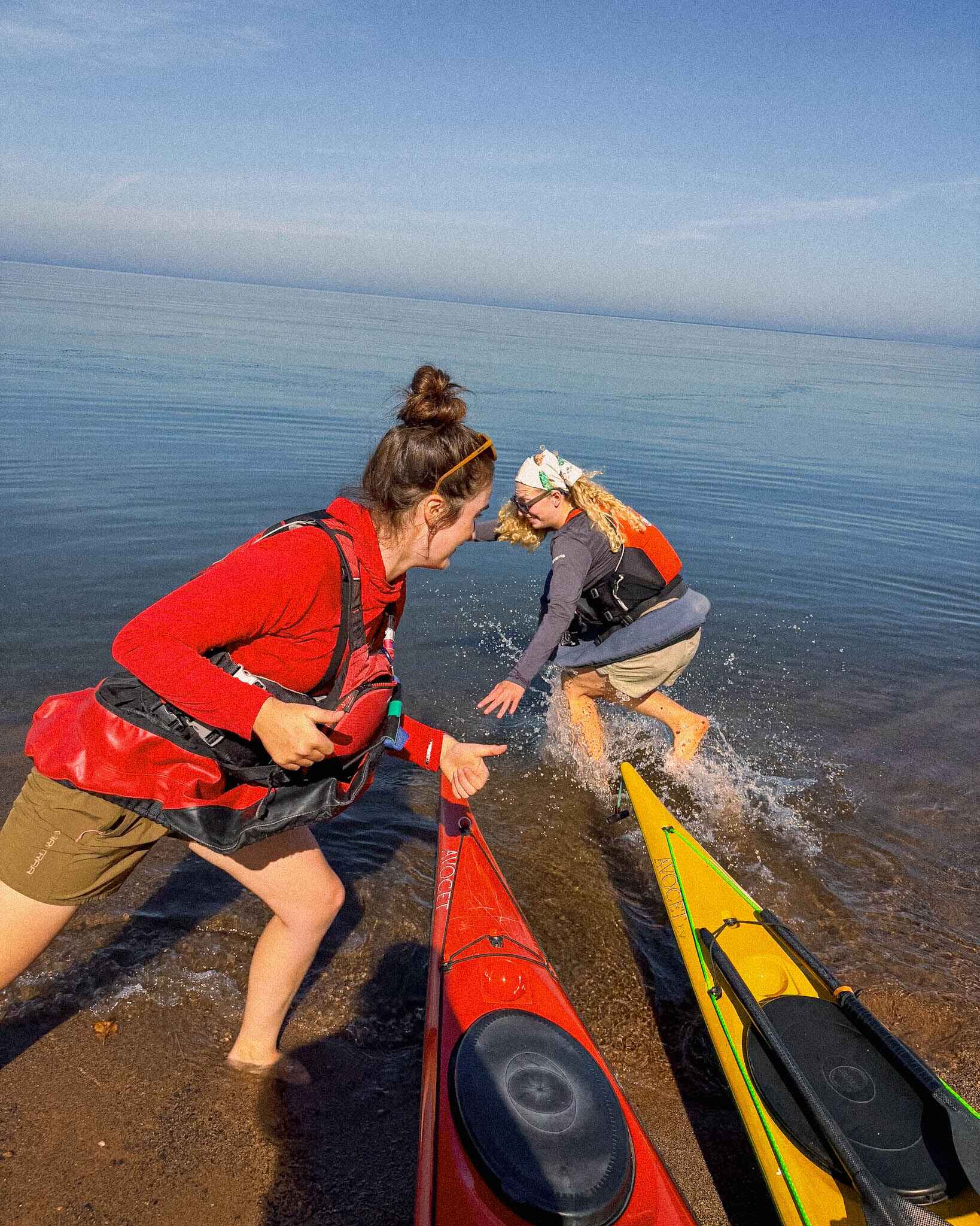 two women play by kayaks on the water