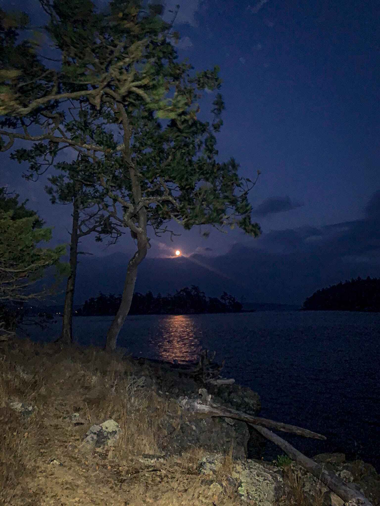 a full moon rises over an island in the distance