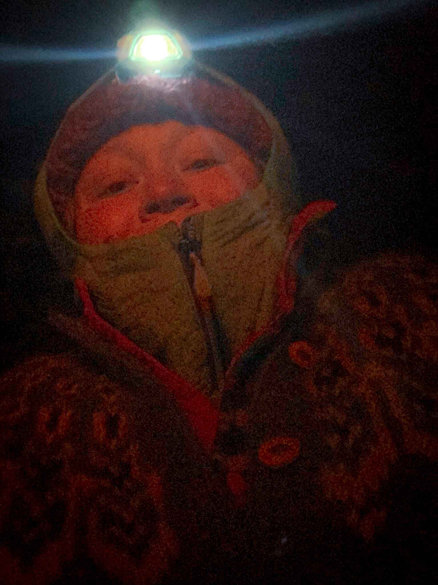 a woman wearing a petzel headlamp winter camping