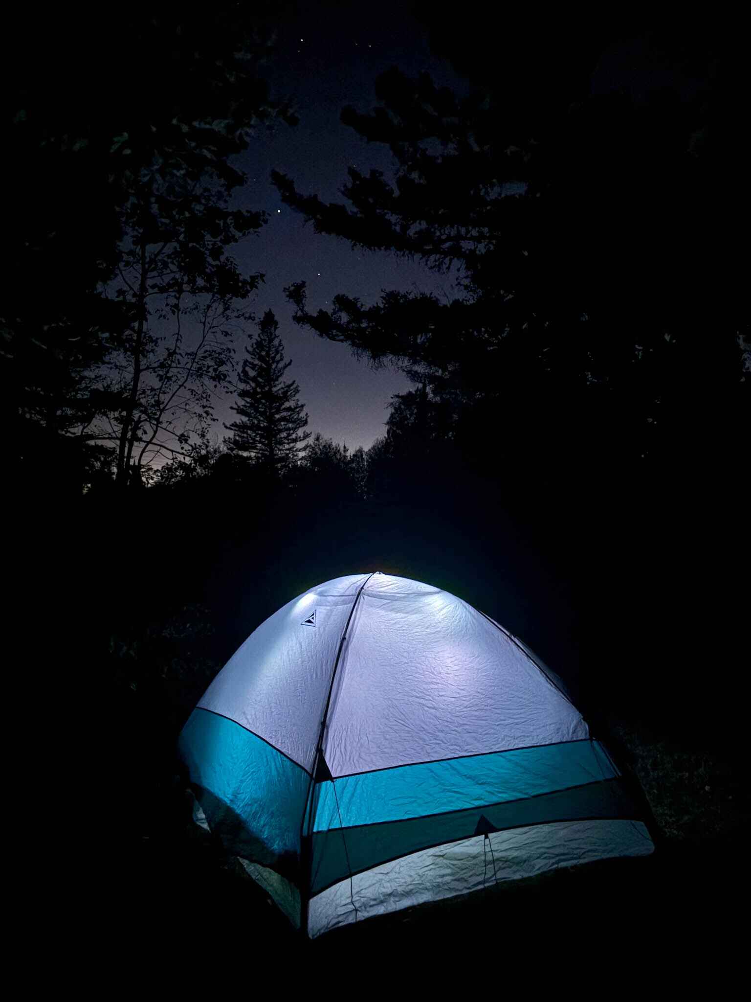 Image of a budget camping tent lit with string lights at night