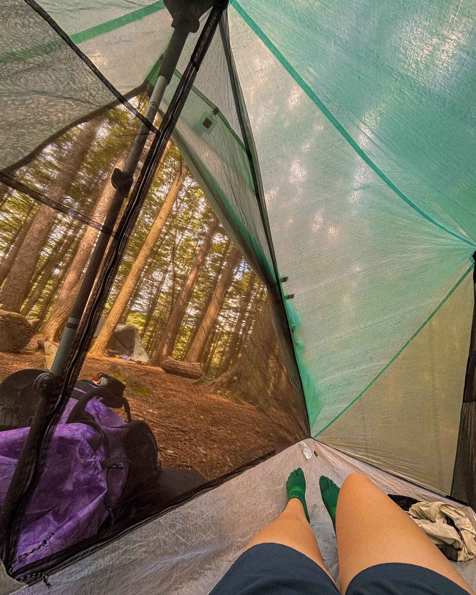 A hiker lounges inside a trekking pole tent
