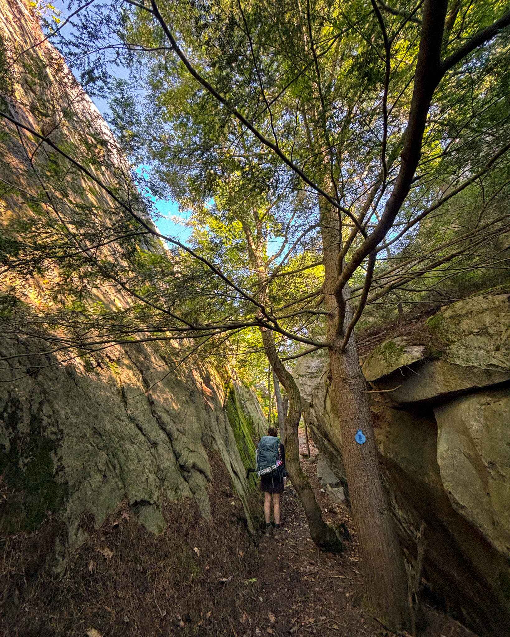 A hiker walks through a canyon like portion of the La Cloche Silhouette Trail