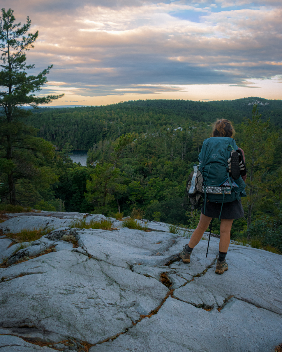 A backpacker on a ridge on the La Cloche silhouette trail at dawn