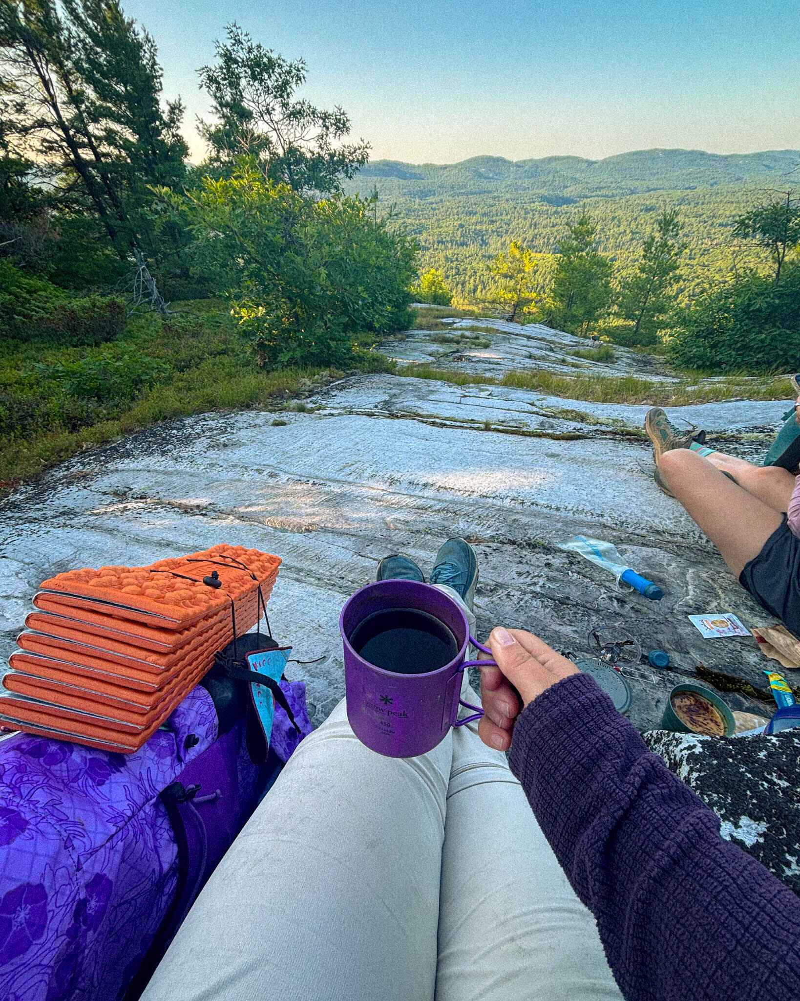 a backpacker drinks coffee on a ridge in the La Cloche mountains