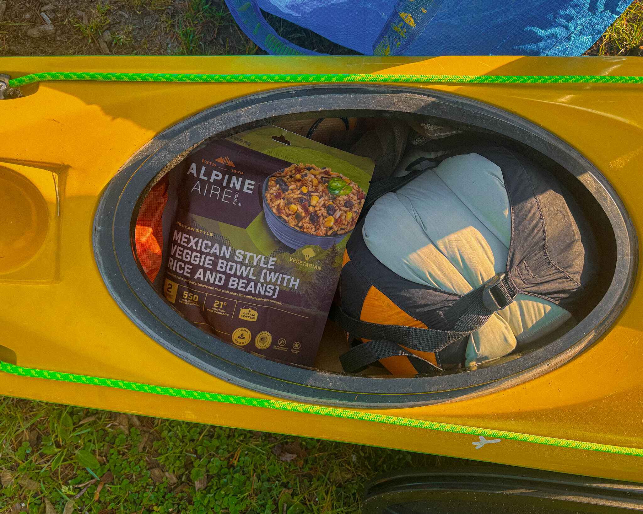 Image of a dehydrated backpacking meal of beans and rice in. akayak hatch next to a compression sack