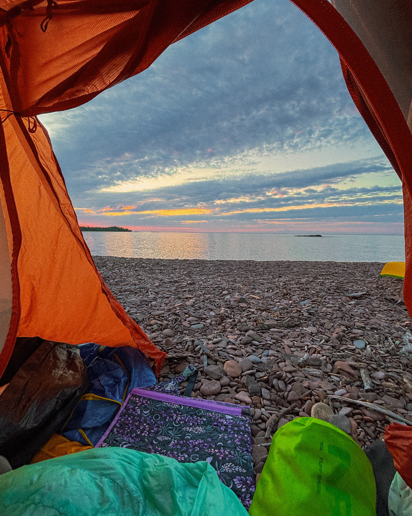 image looking out from a tent at the edge of a lake before sunrise
