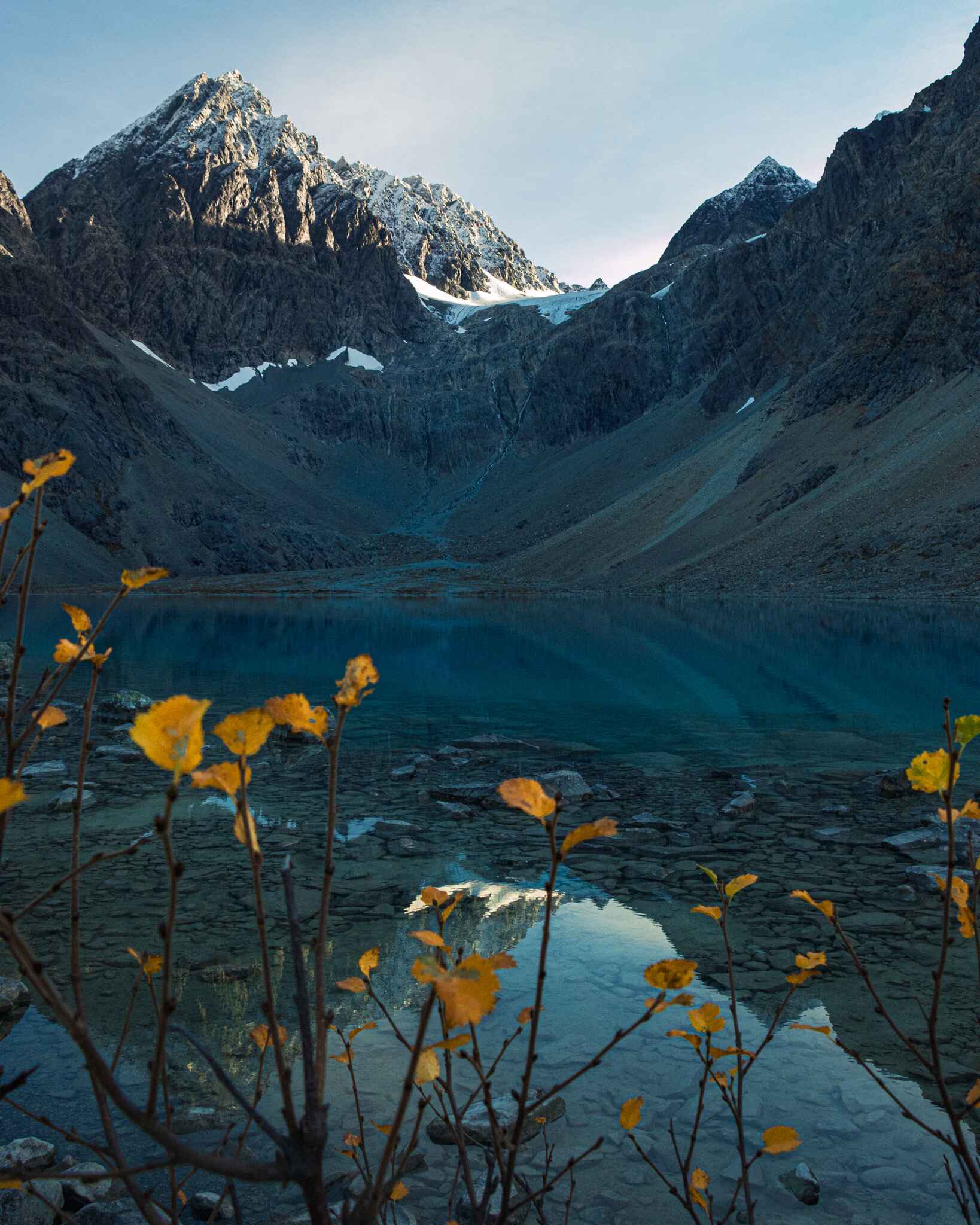 image of a hint of fall color in front of a blue lake in Northern Norway