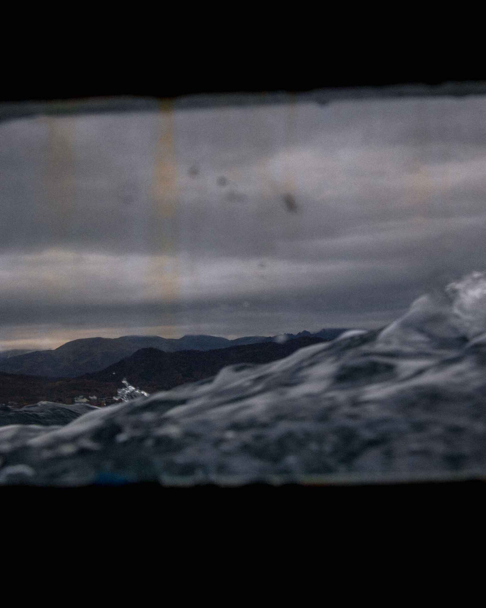 image looking out of the porthole of a boat in Tromso, norway into a choppy fjord