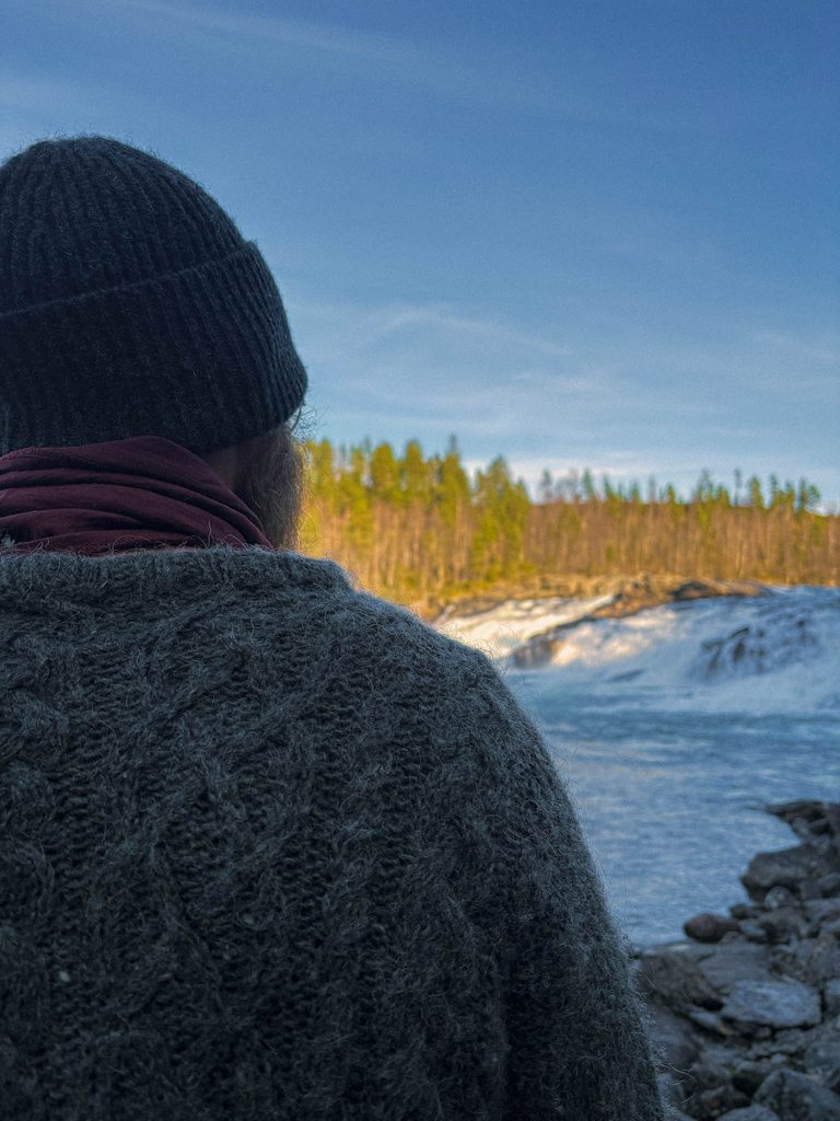 image of a man standing in front of a waterfall in Northern Norway