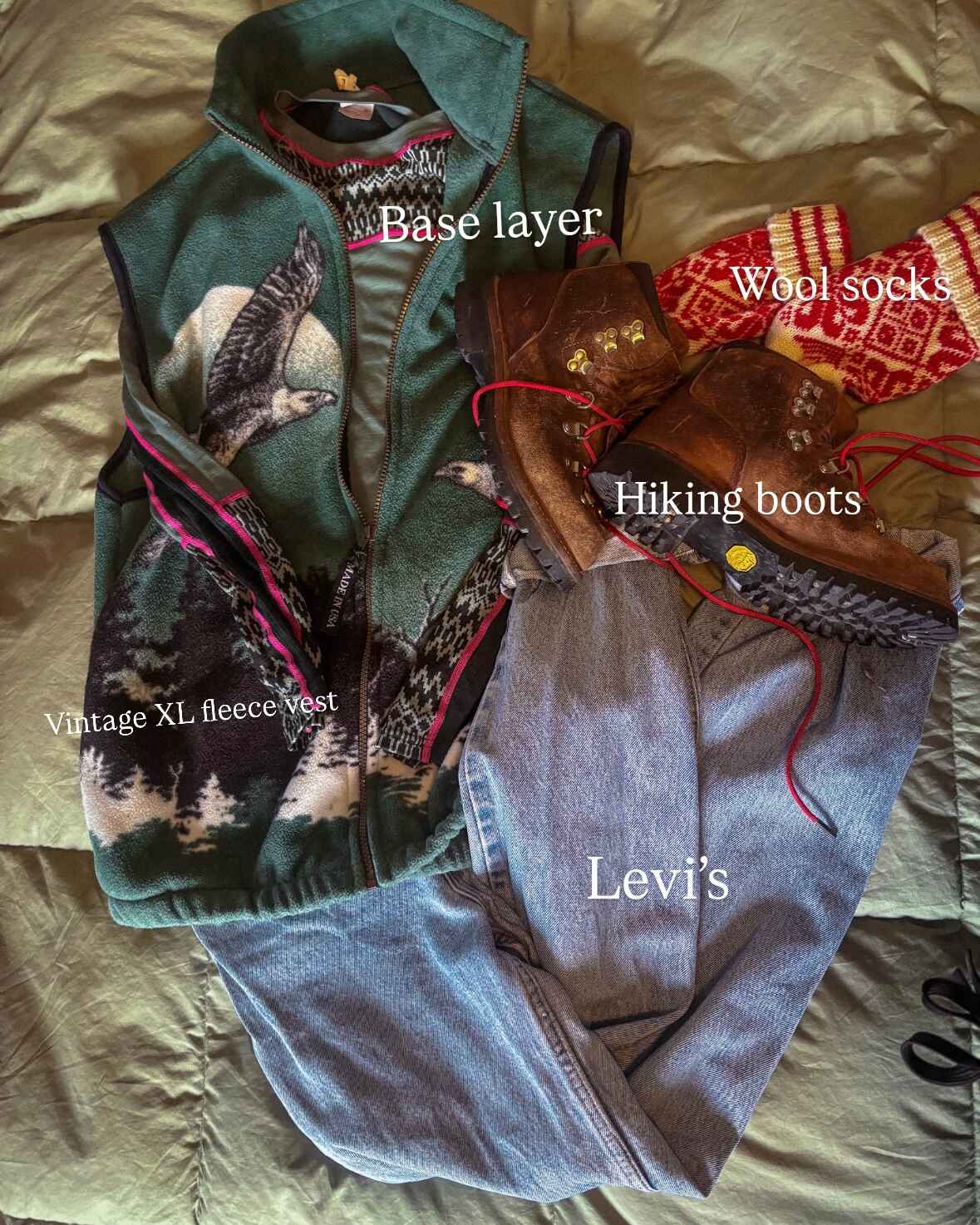 Flat lay of an outfit idea, labeled. Text reads: Base layer, wool socks, hiking boots, Vintage XL fleece vest, Levi's