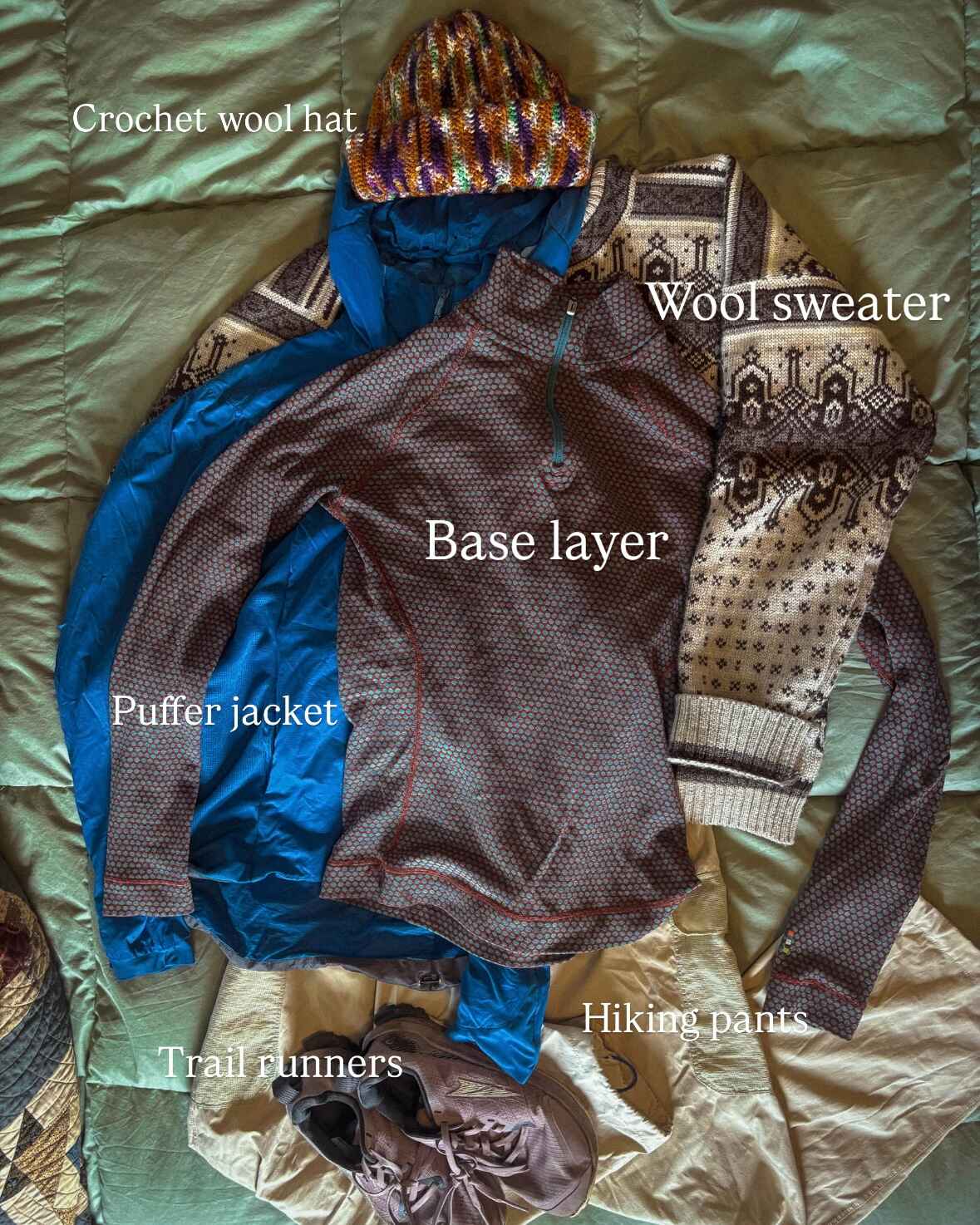 A hiking outfit idea for Norway, labeled. Text reads: crochet wool hat, wool sweater, base layer, puffer jacket, hiking pants, trail runners