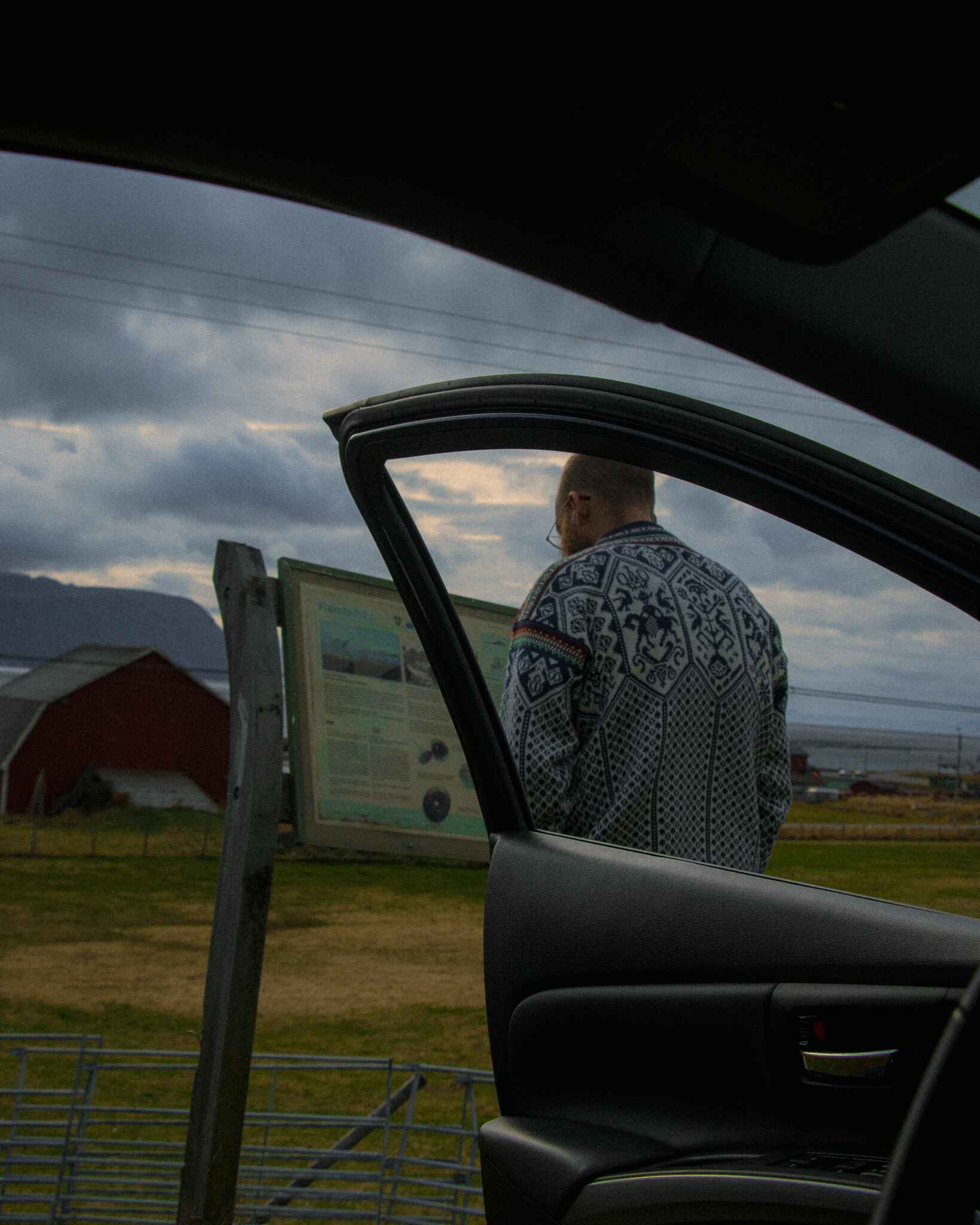 image of a man in a wool sweater framed by an open car door