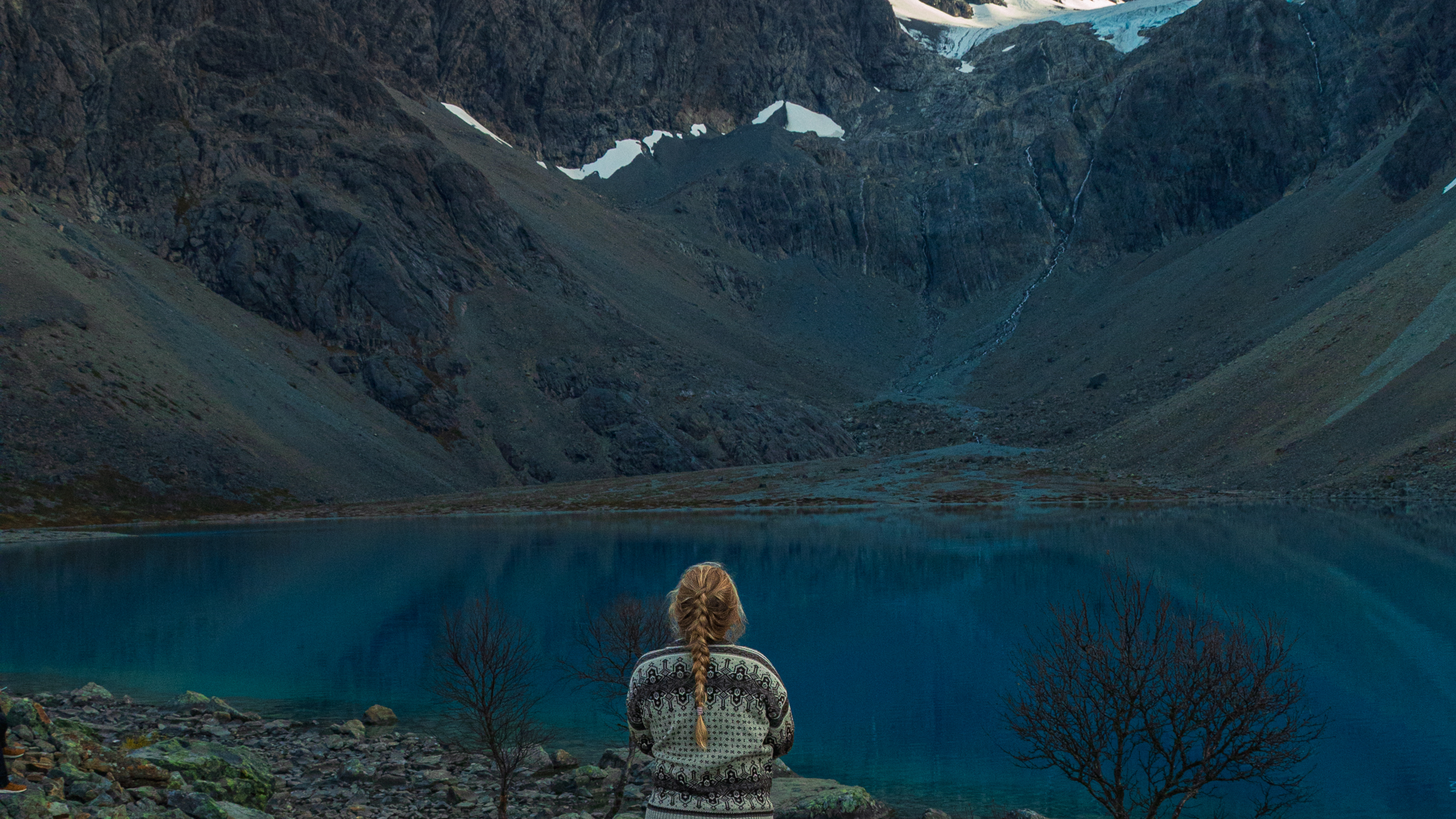 a hiker with a blond braid stands in front of the Blue lake in the Lyngen Alps